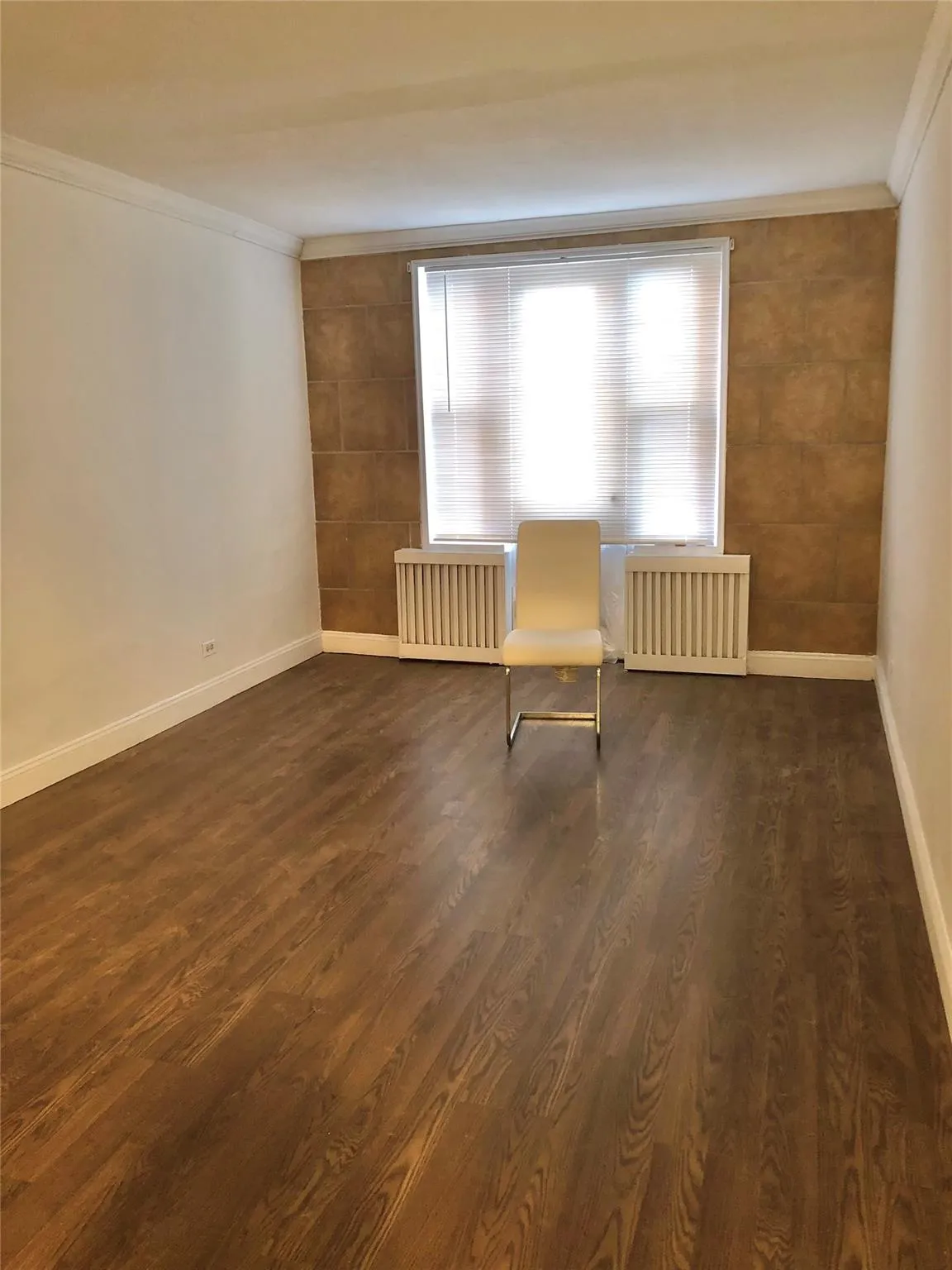 Unfurnished room featuring radiator, dark wood finished floors, crown molding, and baseboards Unfurnished room featuring radiator, dark wood finished floors, crown molding, and baseboards