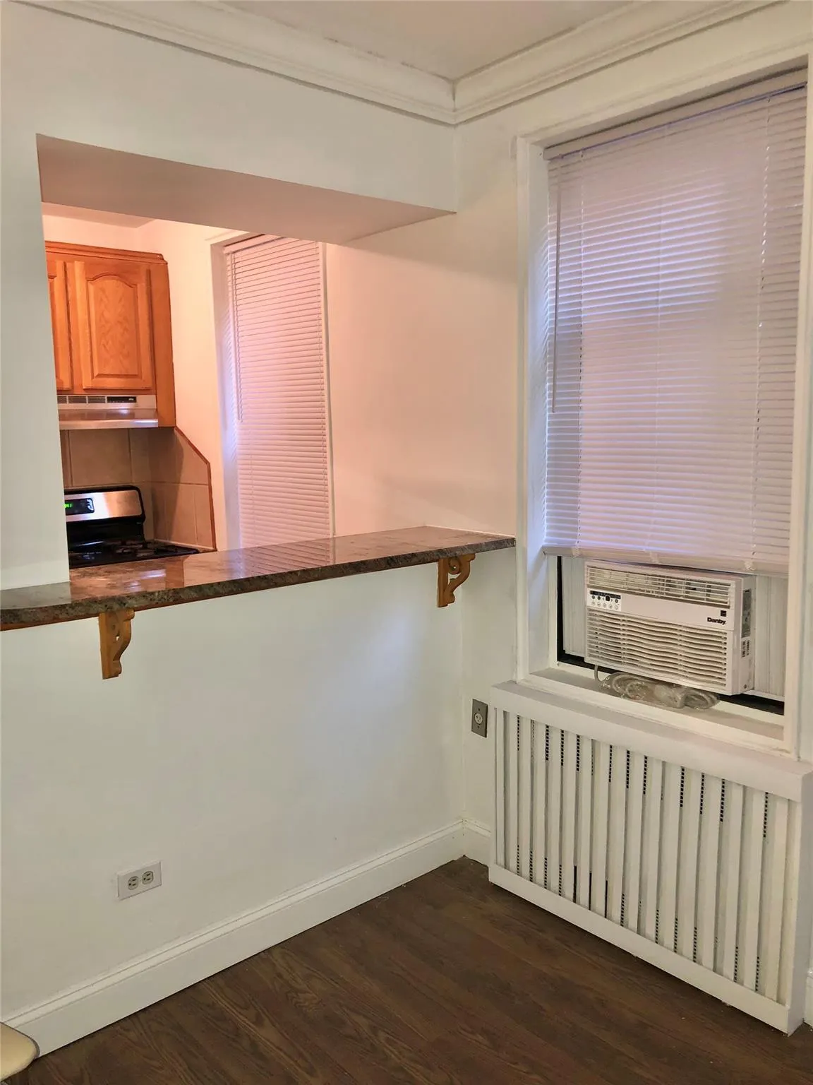 Kitchen featuring ornamental molding, stainless steel range with gas cooktop, cooling unit, baseboards, and dark wood-style flooring Kitchen featuring ornamental molding, stainless steel range with gas cooktop, cooling unit, baseboards, and dark wood-style flooring