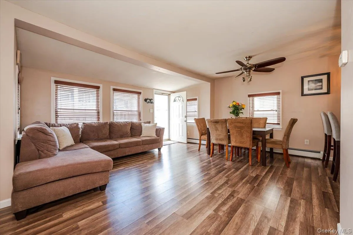 Living room featuring baseboards, a ceiling fan, wood finished floors, and baseboard heating Living room featuring baseboards, a ceiling fan, wood finished floors, and baseboard heating