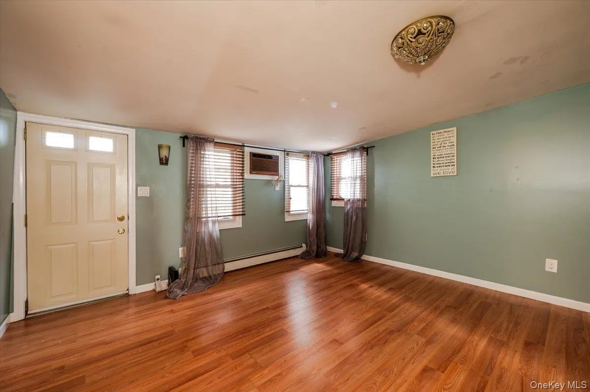 Foyer with baseboards, light wood-type flooring, baseboard heating, and a wall unit AC Foyer with baseboards, light wood-type flooring, baseboard heating, and a wall unit AC