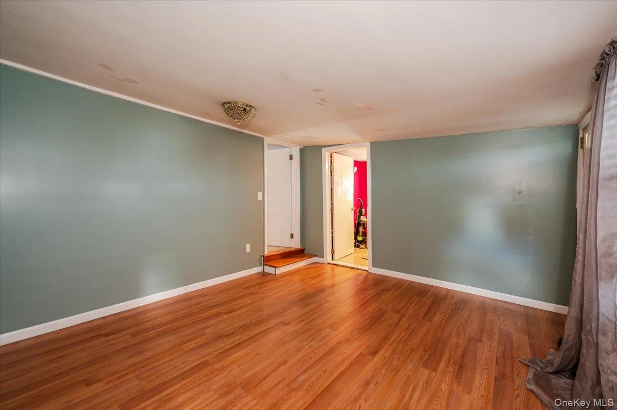 Unfurnished room with wood finished floors and baseboards Unfurnished room with wood finished floors and baseboards
