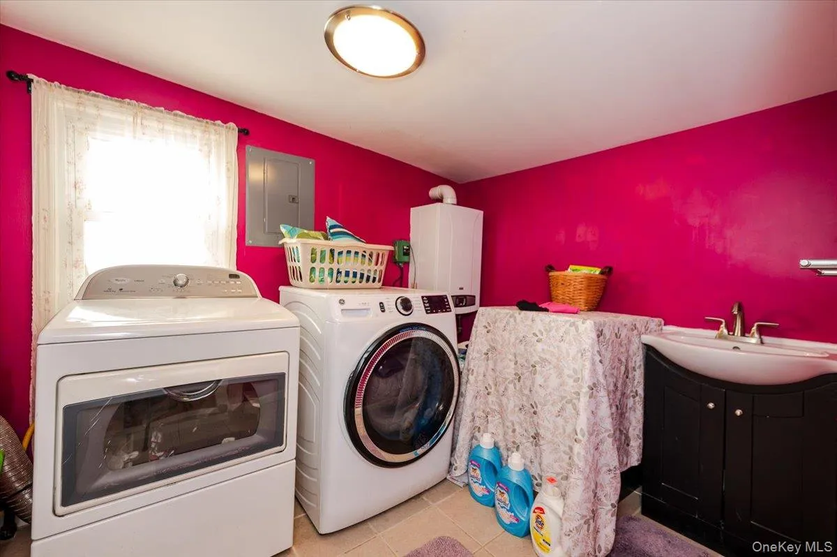 Laundry room with a sink, electric panel, washer and dryer, tile patterned flooring, and laundry area, Heating system - tankless Laundry room with a sink, electric panel, washer and dryer, tile patterned flooring, and laundry area, Heating system - tankless
