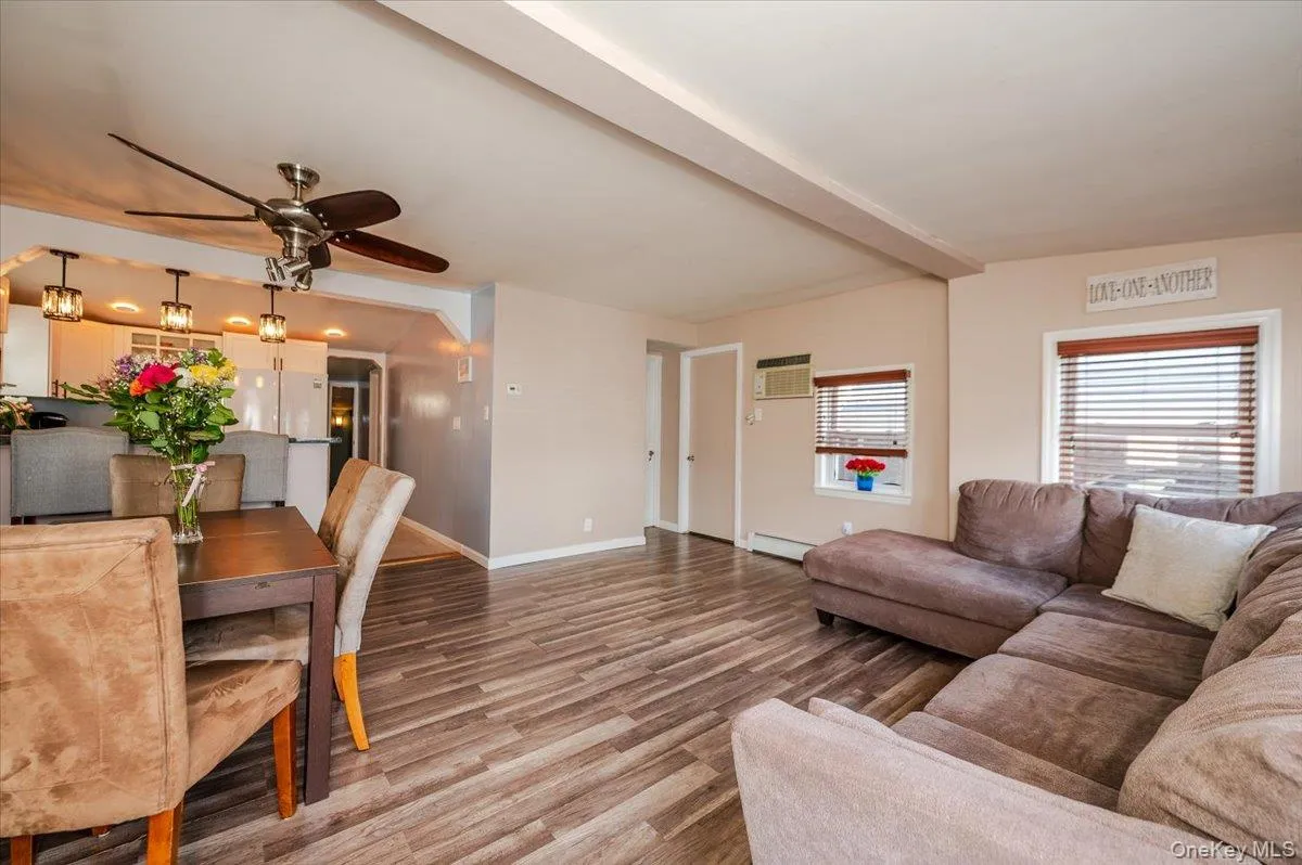 Living room featuring light wood finished floors, baseboards, a wall mounted air conditioner, baseboard heating, and ceiling fan Living room featuring light wood finished floors, baseboards, a wall mounted air conditioner, baseboard heating, and ceiling fan