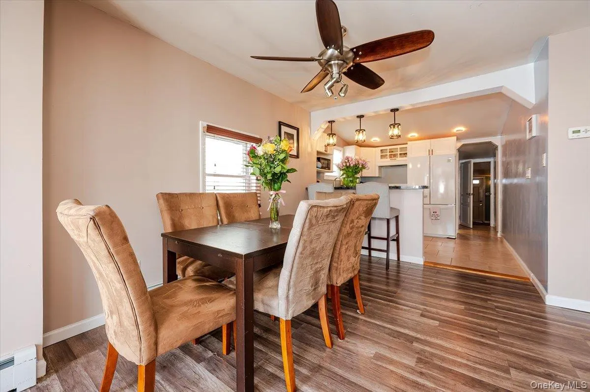 Dining space with baseboards, baseboard heating, wood finished floors, and ceiling fan Dining space with baseboards, baseboard heating, wood finished floors, and ceiling fan