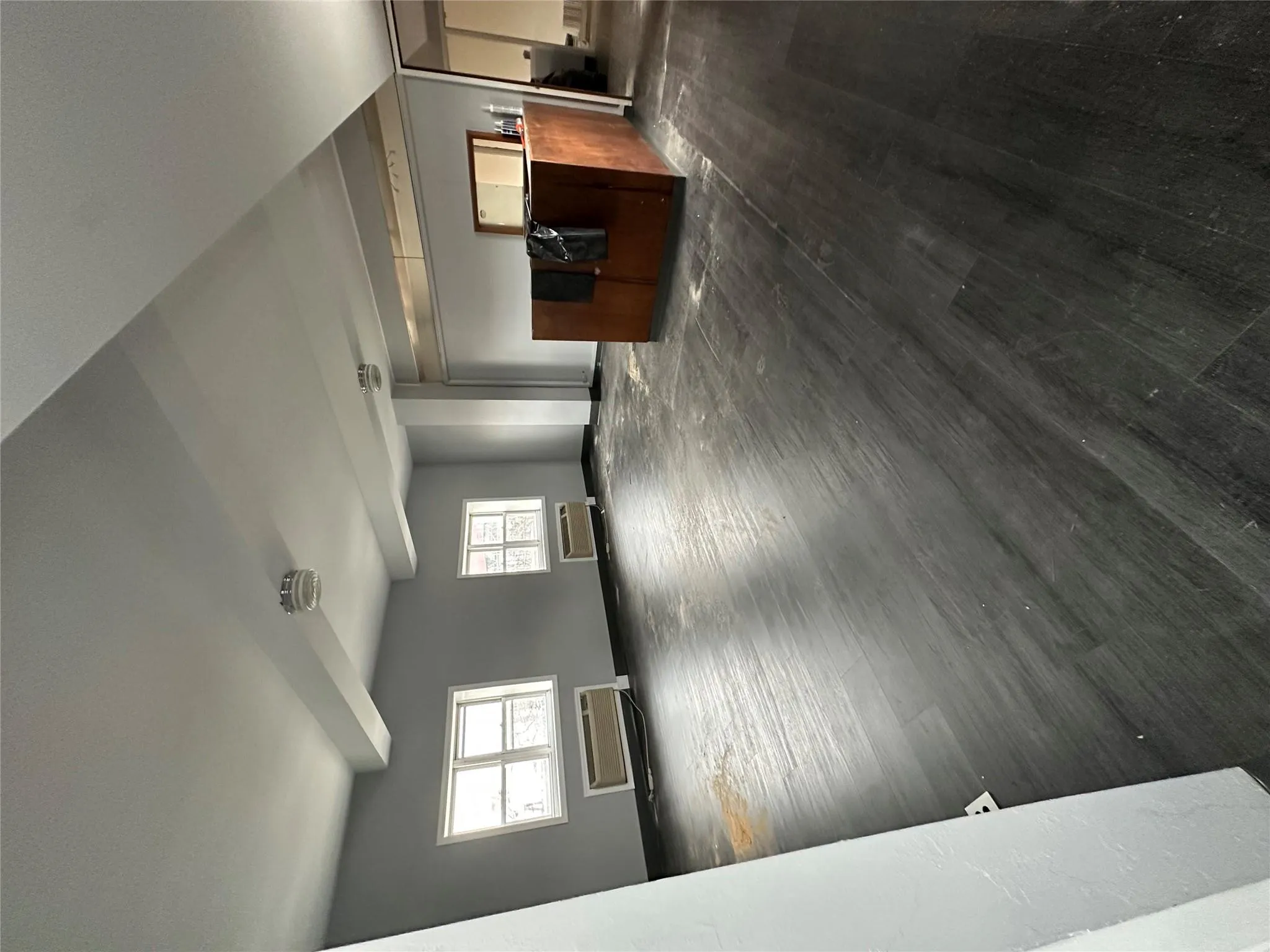 Unfurnished living room with baseboards, dark wood-style flooring, and a wall mounted AC Unfurnished living room with baseboards, dark wood-style flooring, and a wall mounted AC