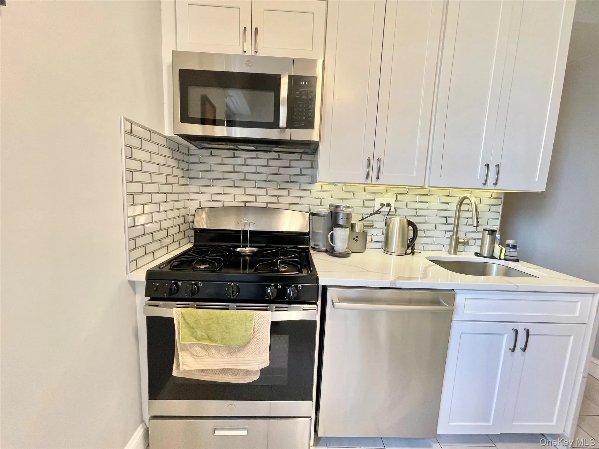 Kitchen featuring tasteful backsplash, light stone countertops, stainless steel appliances, and a sink Kitchen featuring tasteful backsplash, light stone countertops, stainless steel appliances, and a sink