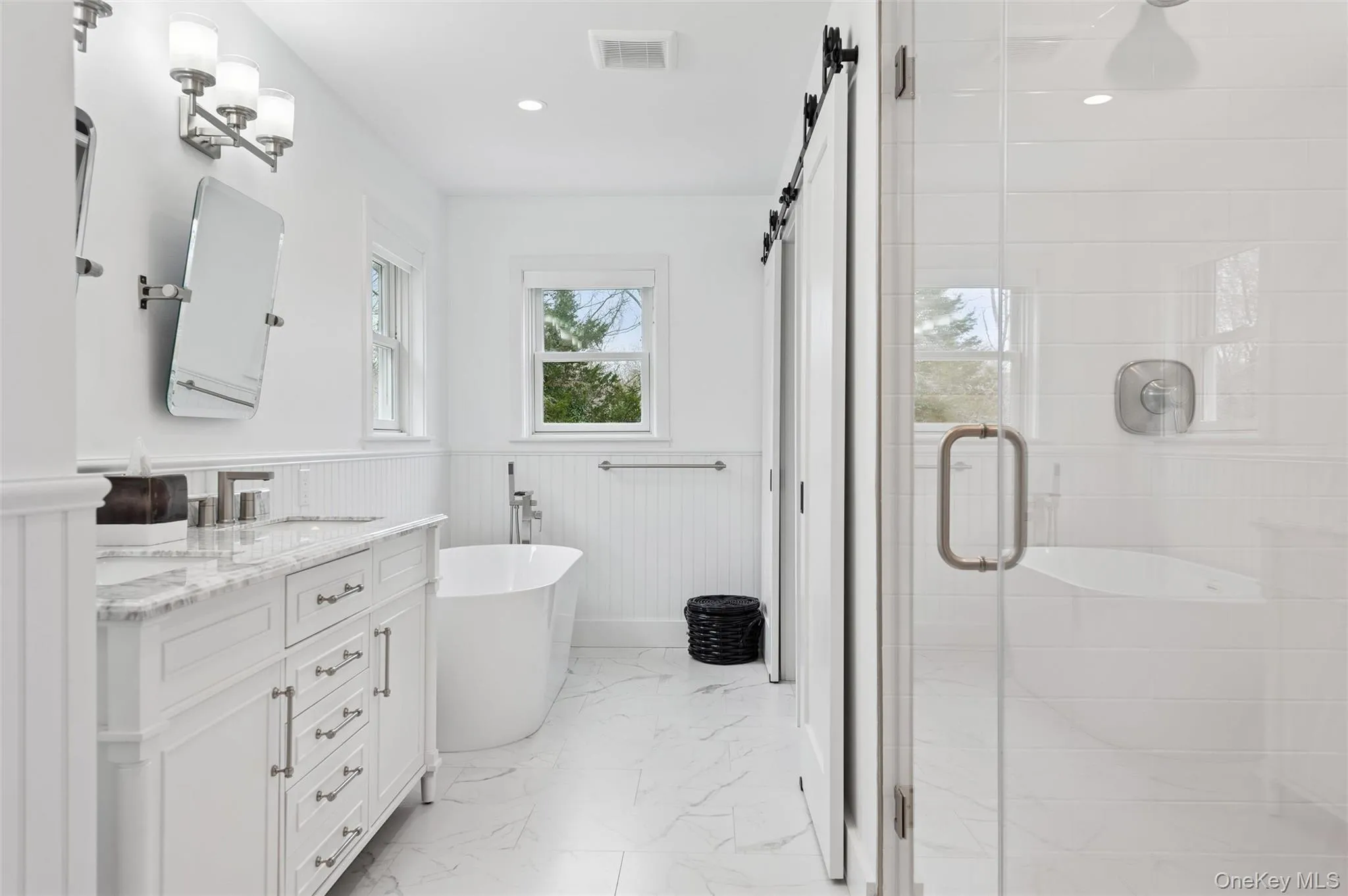 Bathroom featuring a shower stall, a freestanding bath, visible vents, vanity, and wainscoting Bathroom featuring a shower stall, a freestanding bath, visible vents, vanity, and wainscoting