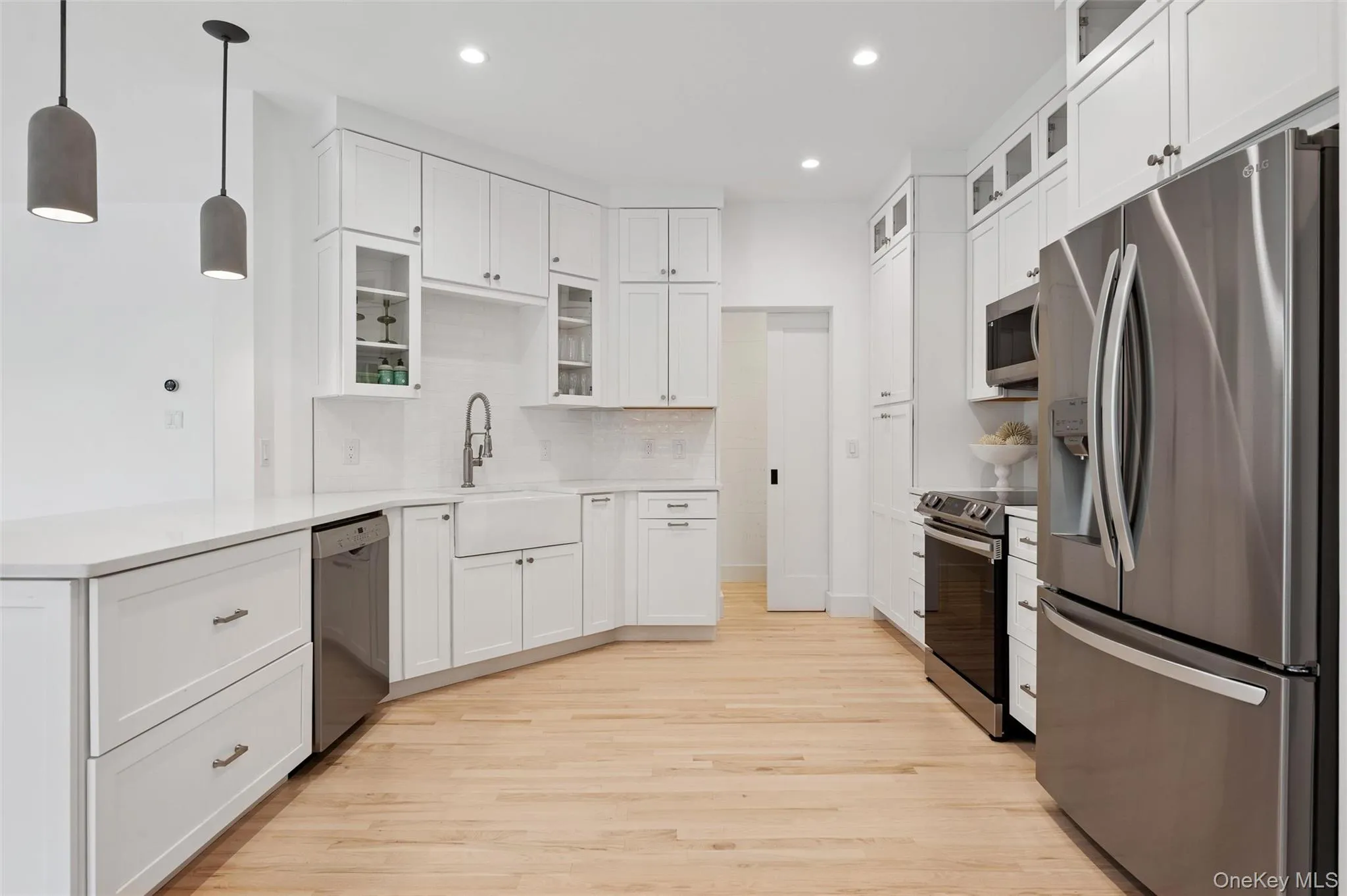 Kitchen with light wood-style floors, stainless steel appliances, backsplash, a peninsula, and recessed lighting Kitchen with light wood-style floors, stainless steel appliances, backsplash, a peninsula, and recessed lighting