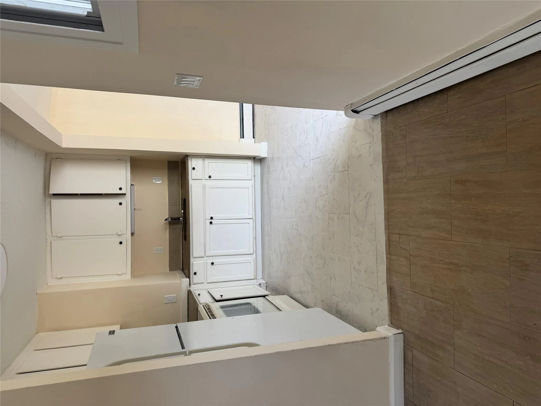 Kitchen featuring a sink, stove, a baseboard heating unit, and white cabinetry Kitchen featuring a sink, stove, a baseboard heating unit, and white cabinetry