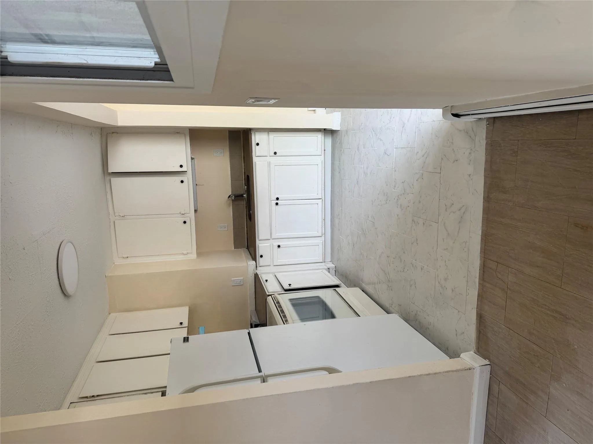 Kitchen with fridge, stove, a baseboard radiator, white cabinetry, and a sink Kitchen with fridge, stove, a baseboard radiator, white cabinetry, and a sink