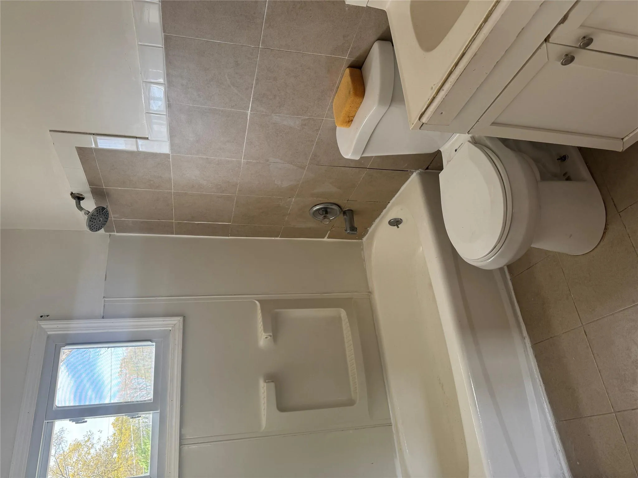 Bathroom with tile patterned flooring, vanity, toilet, tile walls, and washtub / shower combination Bathroom with tile patterned flooring, vanity, toilet, tile walls, and washtub / shower combination
