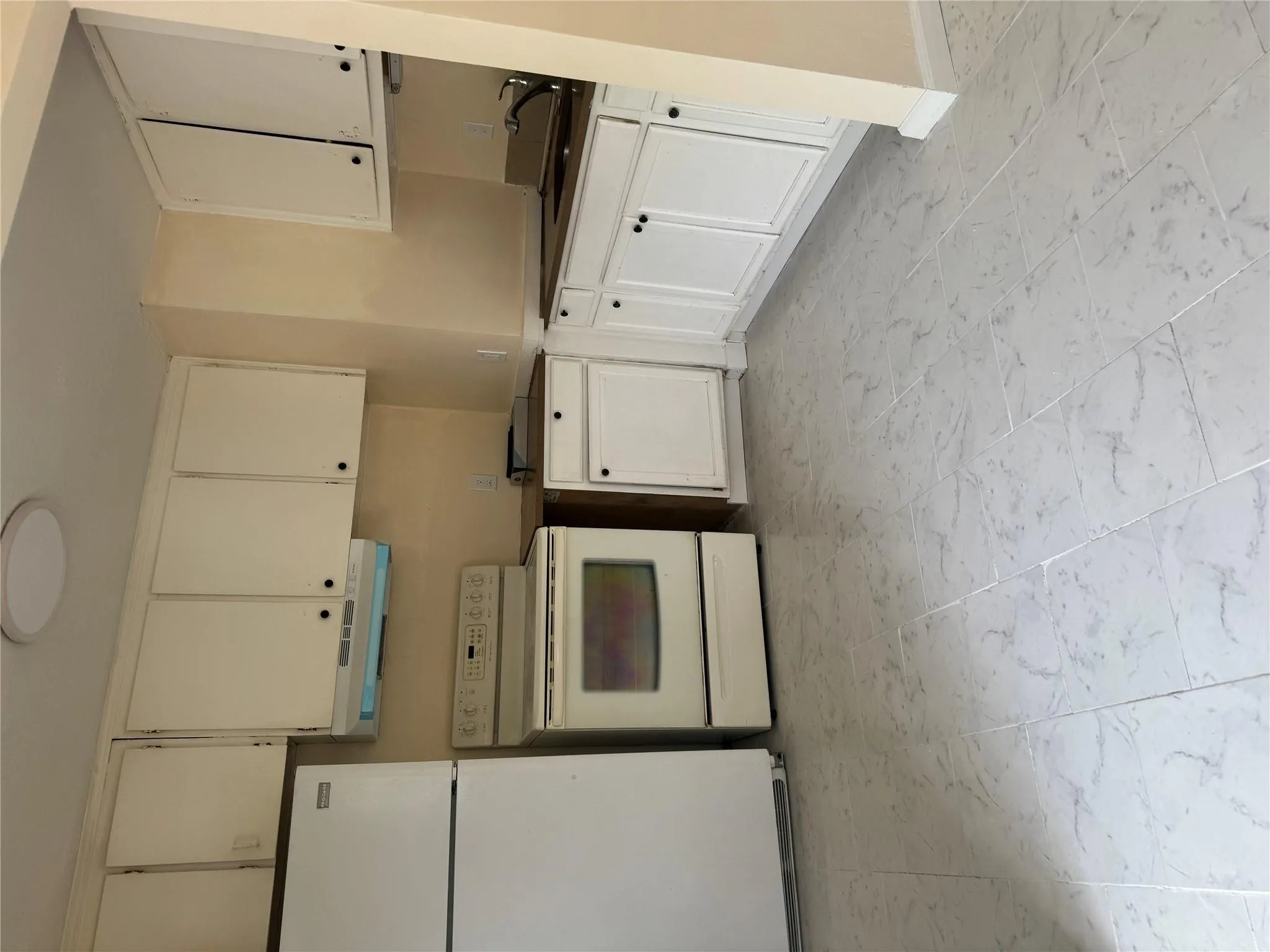 Kitchen featuring stove, fridge, extractor fan, and marble finish floor Kitchen featuring stove, fridge, extractor fan, and marble finish floor