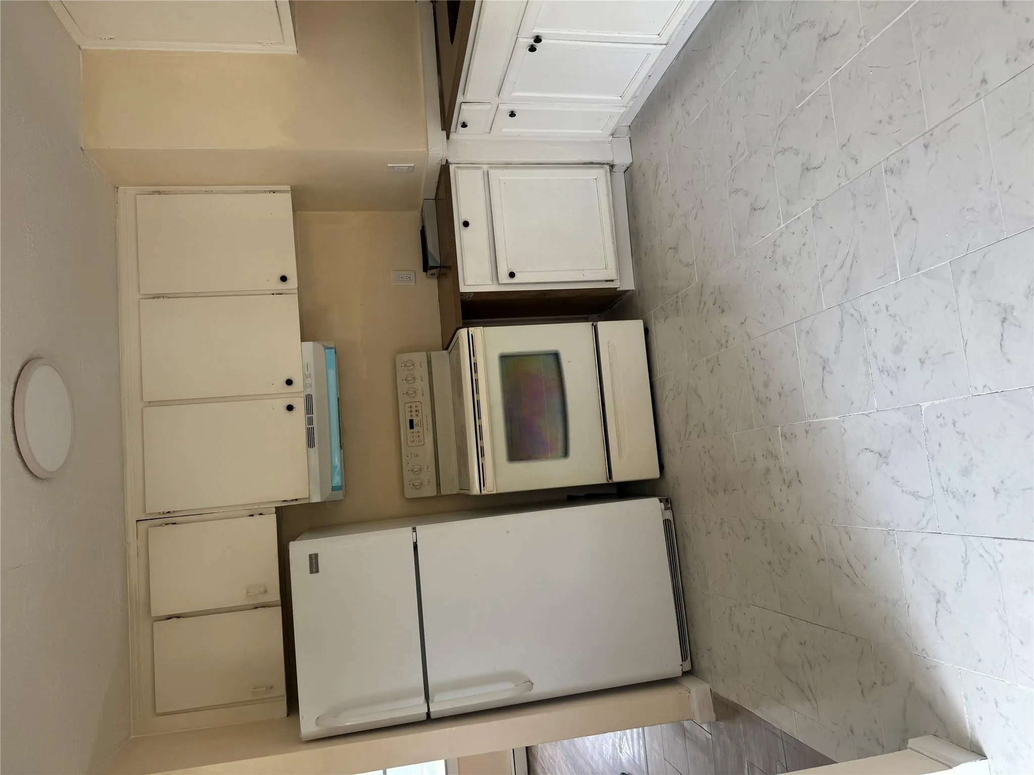 Kitchen with white electric stove, range hood, refrigerator, marble finish floor, and cream cabinetry Kitchen with white electric stove, range hood, refrigerator, marble finish floor, and cream cabinetry