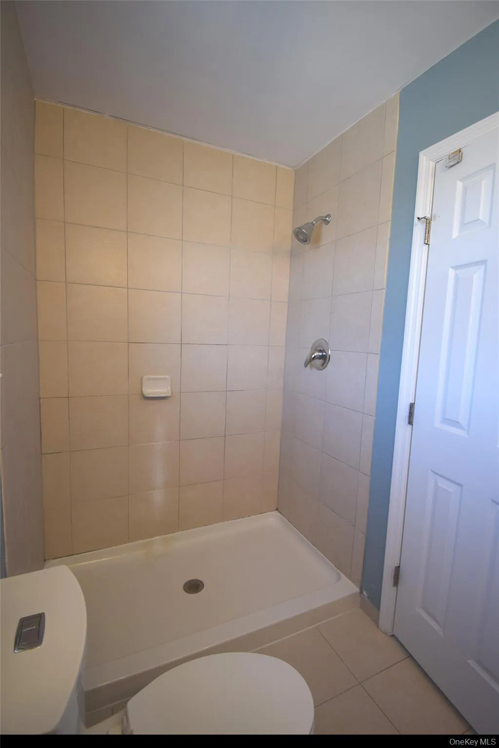 Bathroom with a tile shower, toilet, and tile patterned floors Bathroom with a tile shower, toilet, and tile patterned floors