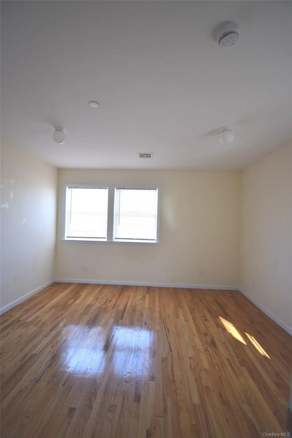 Spare room featuring baseboards, wood finished floors, and visible vents Spare room featuring baseboards, wood finished floors, and visible vents