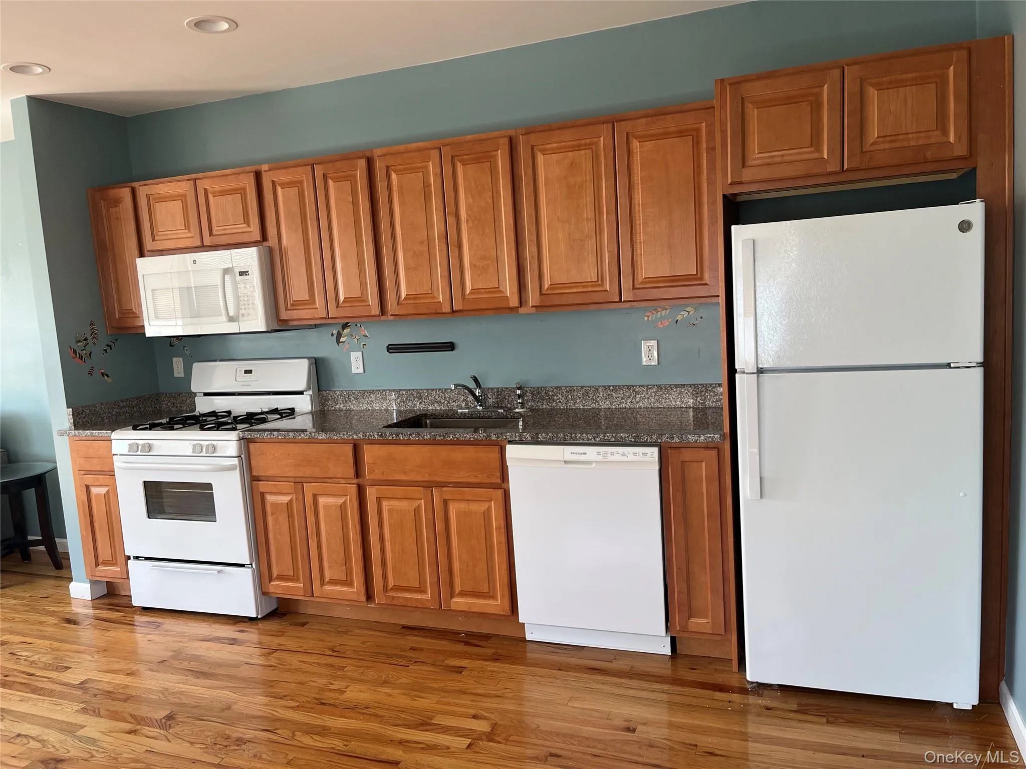 Kitchen featuring recessed lighting, light wood finished floors, a sink, and white appliances Kitchen featuring recessed lighting, light wood finished floors, a sink, and white appliances
