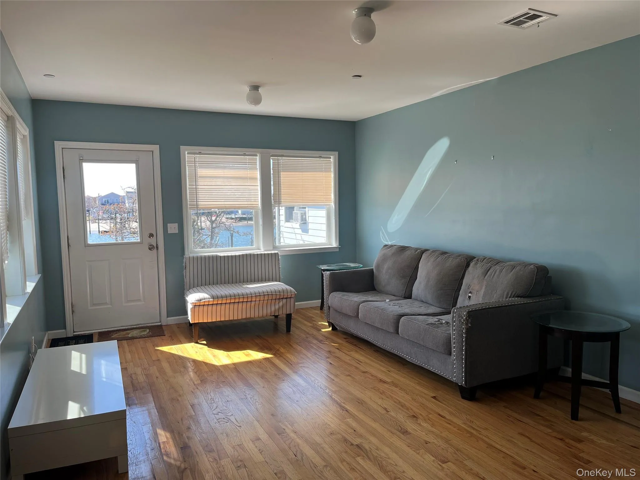 Living area featuring plenty of natural light, wood finished floors, and visible vents Living area featuring plenty of natural light, wood finished floors, and visible vents