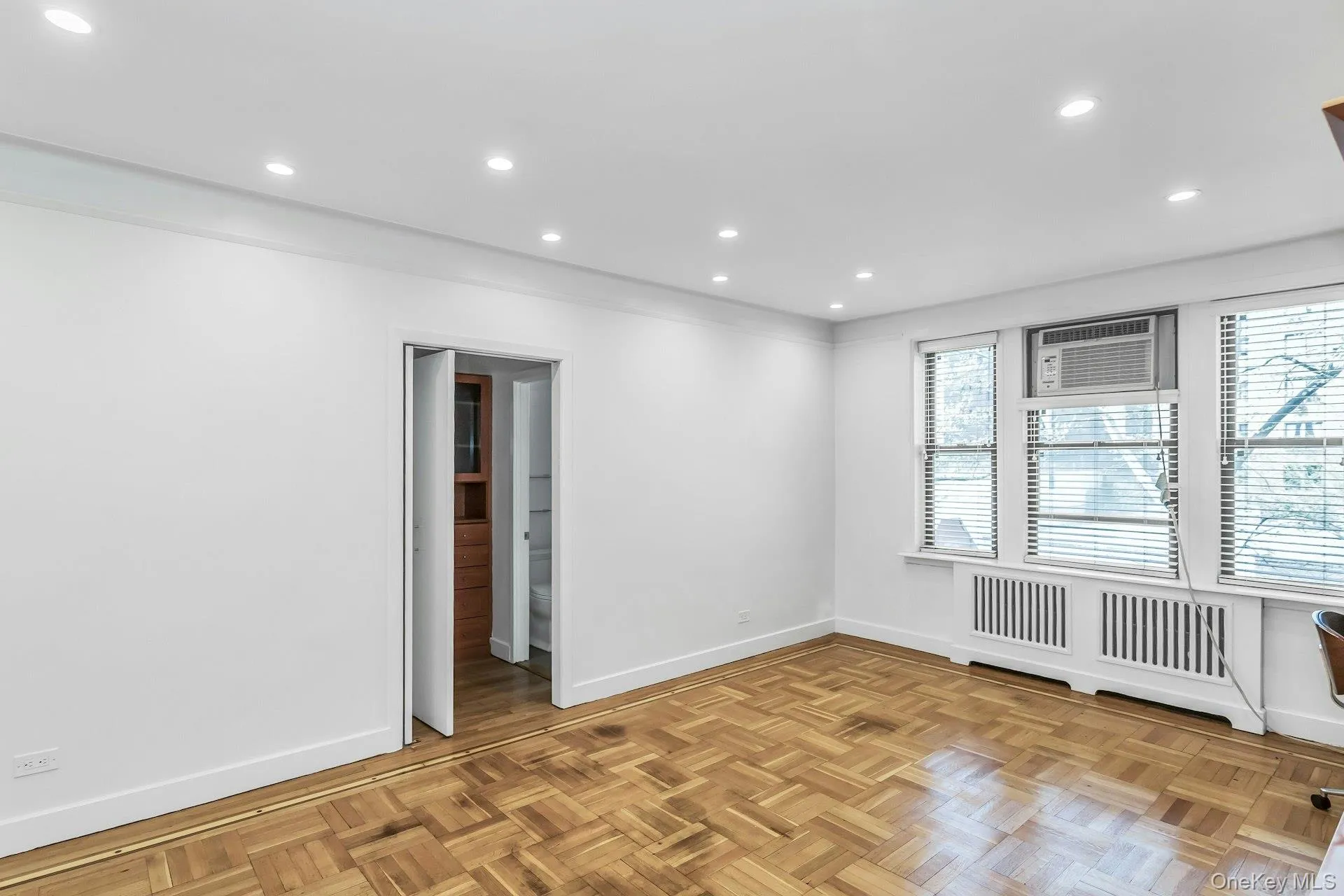 Spare room with baseboards, recessed lighting, and a wall mounted air conditioner Spare room with baseboards, recessed lighting, and a wall mounted air conditioner