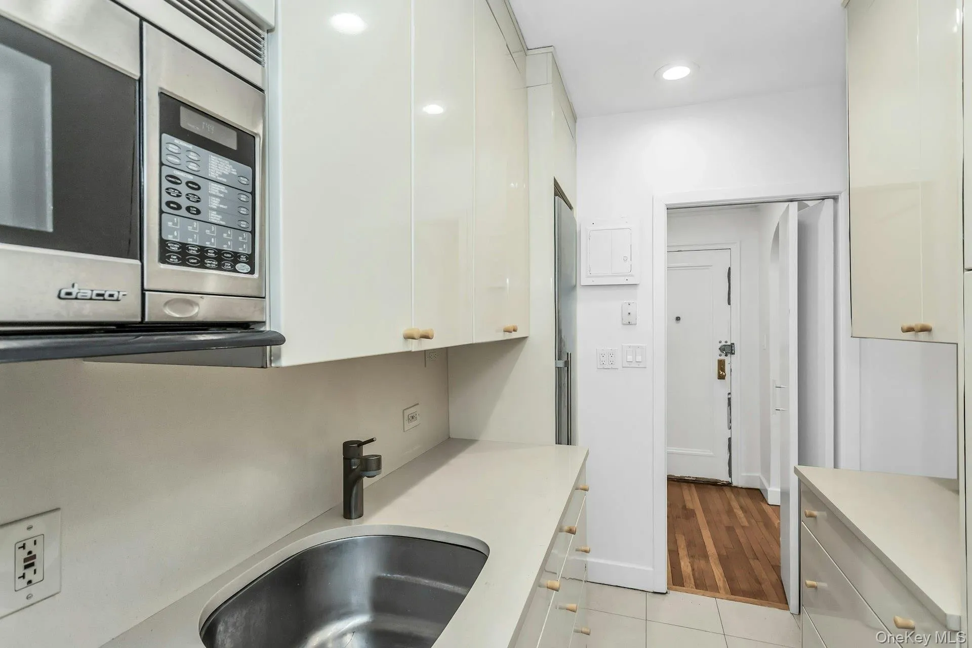 Kitchen with white cabinets, light countertops, light tile patterned floors, stainless steel microwave, and a sink Kitchen with white cabinets, light countertops, light tile patterned floors, stainless steel microwave, and a sink
