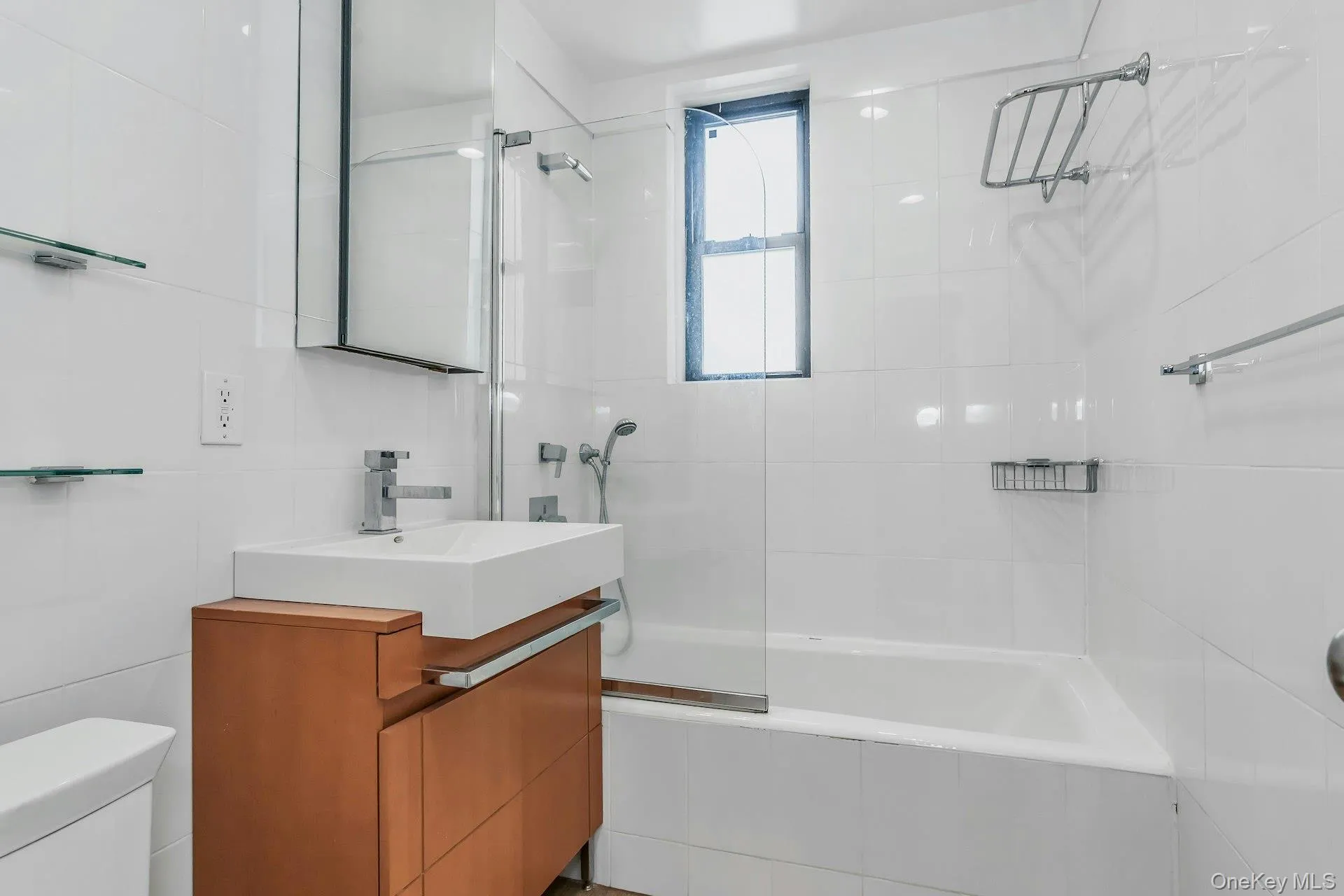 Full bath featuring tile walls, vanity, tiled shower / bath, and toilet Full bath featuring tile walls, vanity, tiled shower / bath, and toilet