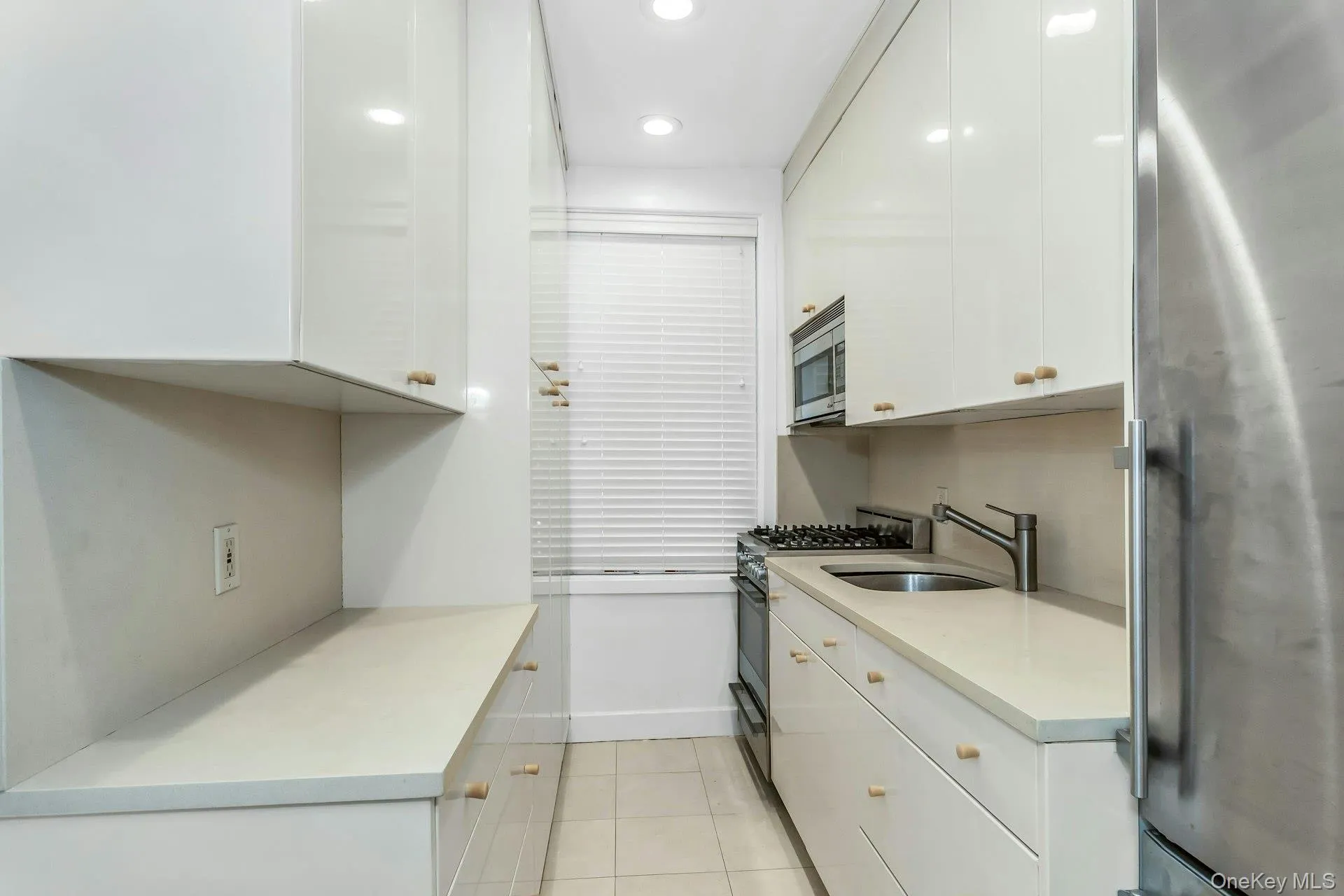 Kitchen featuring white cabinets, a sink, appliances with stainless steel finishes, and light tile patterned flooring Kitchen featuring white cabinets, a sink, appliances with stainless steel finishes, and light tile patterned flooring