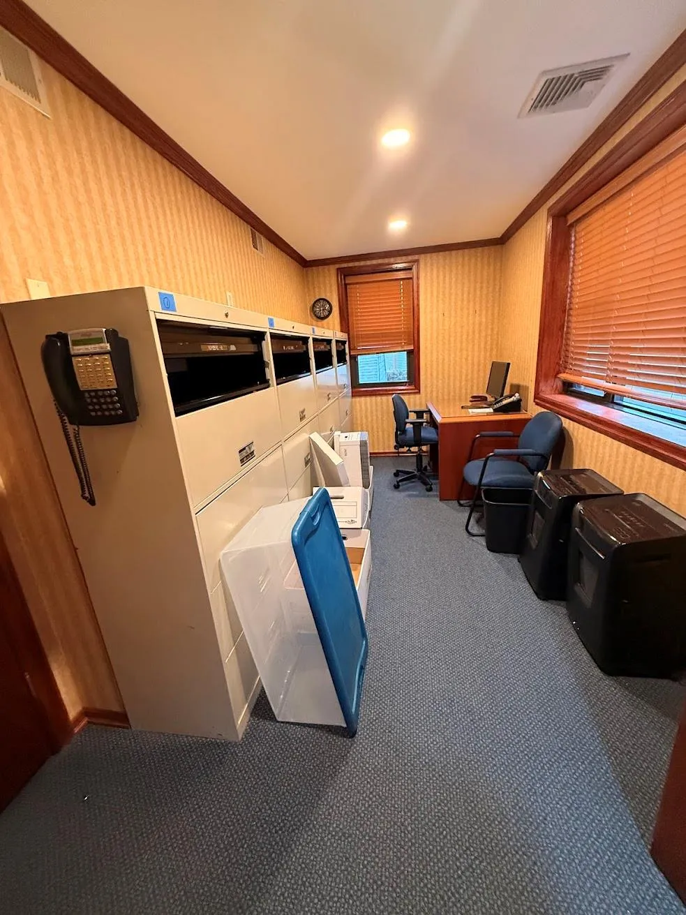 Office space with vaulted ceiling, wallpapered walls, ornamental molding, carpet flooring, and visible vents Office space with vaulted ceiling, wallpapered walls, ornamental molding, carpet flooring, and visible vents