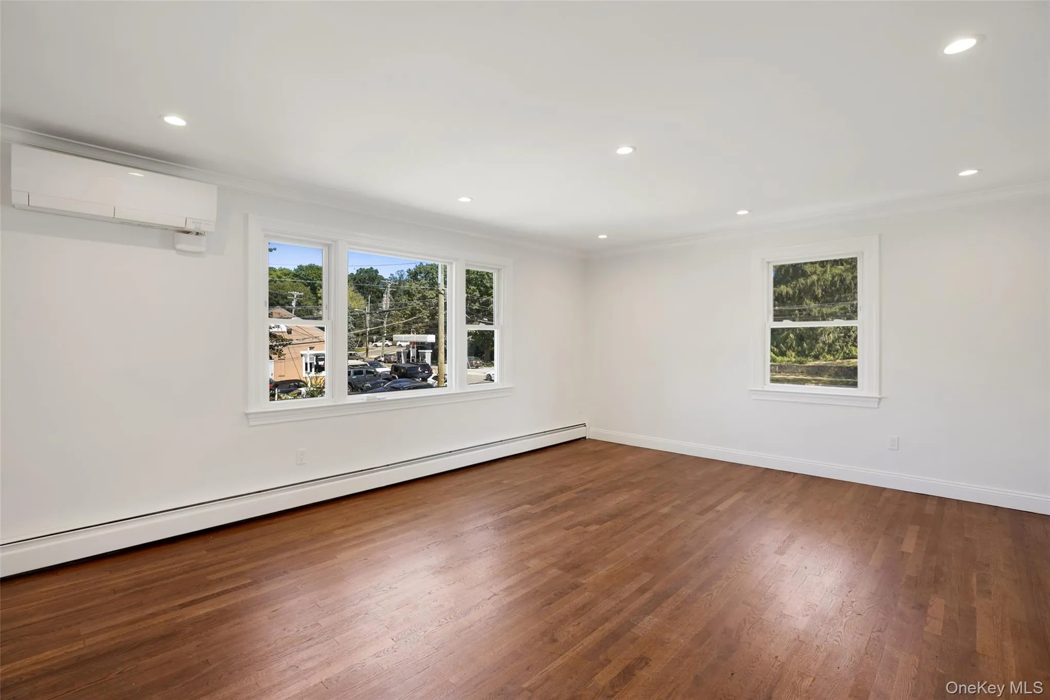 Unfurnished room featuring baseboard heating, crown molding, dark wood-style floors, recessed lighting, and a wall unit AC Unfurnished room featuring baseboard heating, crown molding, dark wood-style floors, recessed lighting, and a wall unit AC