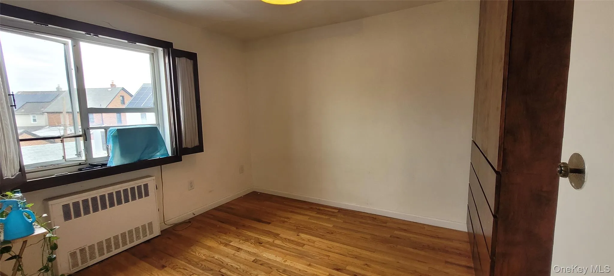 Spare room with light wood finished floors, baseboards, and radiator Spare room with light wood finished floors, baseboards, and radiator