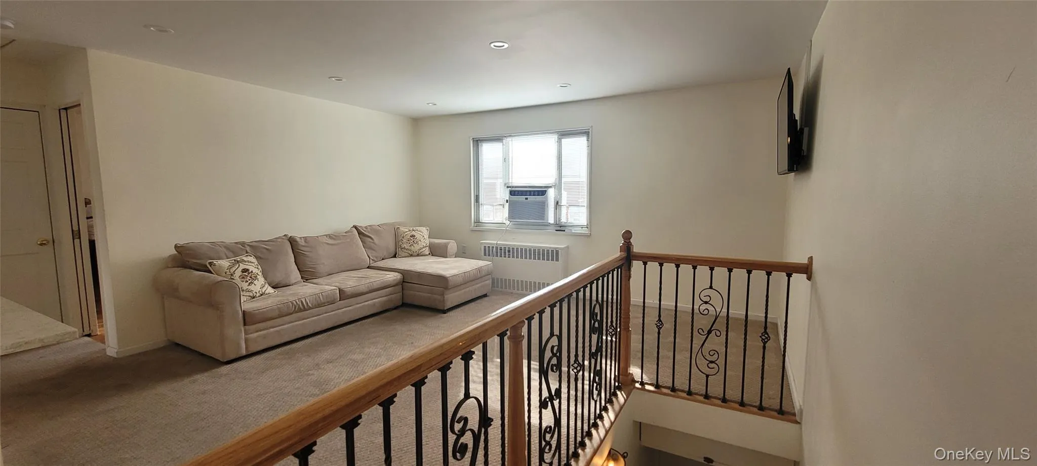 Carpeted living room featuring radiator heating unit and cooling unit Carpeted living room featuring radiator heating unit and cooling unit