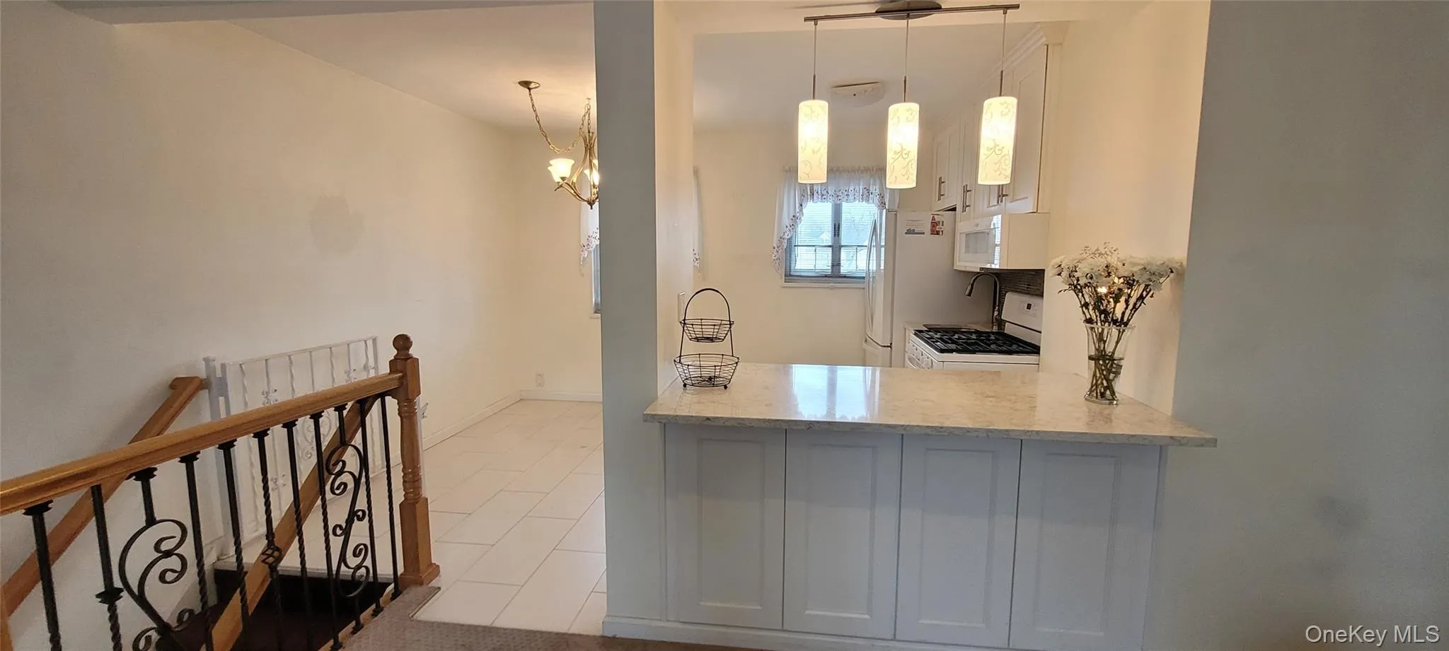 Kitchen with tile patterned flooring, white appliances, light stone countertops, a peninsula, and hanging light fixtures Kitchen with tile patterned flooring, white appliances, light stone countertops, a peninsula, and hanging light fixtures