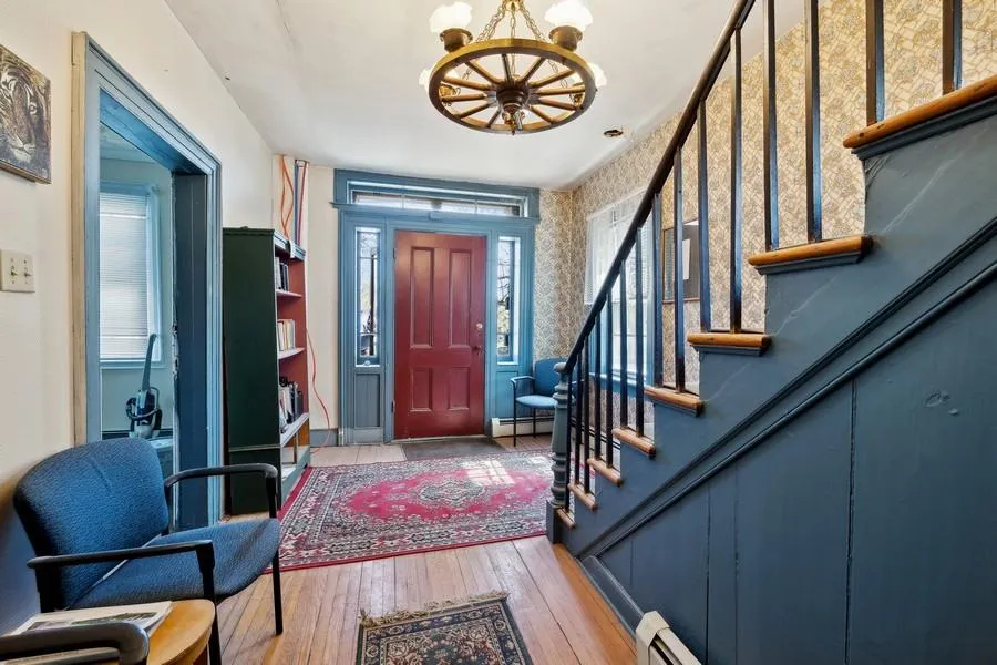 Entryway featuring a chandelier, wallpapered walls, baseboard heating, stairs, and hardwood / wood-style flooring Entryway featuring a chandelier, wallpapered walls, baseboard heating, stairs, and hardwood / wood-style flooring