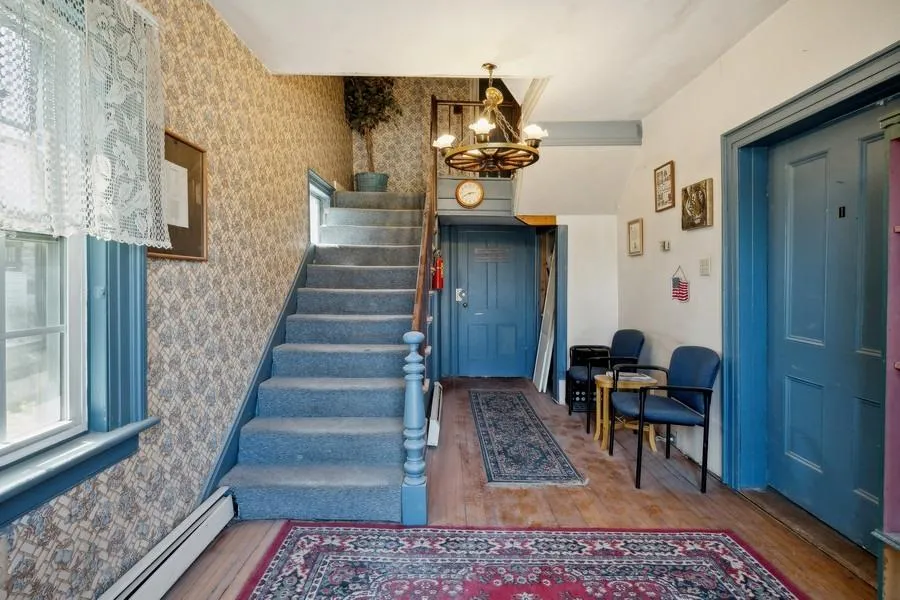 Entrance foyer with a baseboard heating unit, wood finished floors, an inviting chandelier, and stairs. Office door on right hand side of photo. Entrance foyer with a baseboard heating unit, wood finished floors, an inviting chandelier, and stairs. Office door on right hand side of photo.