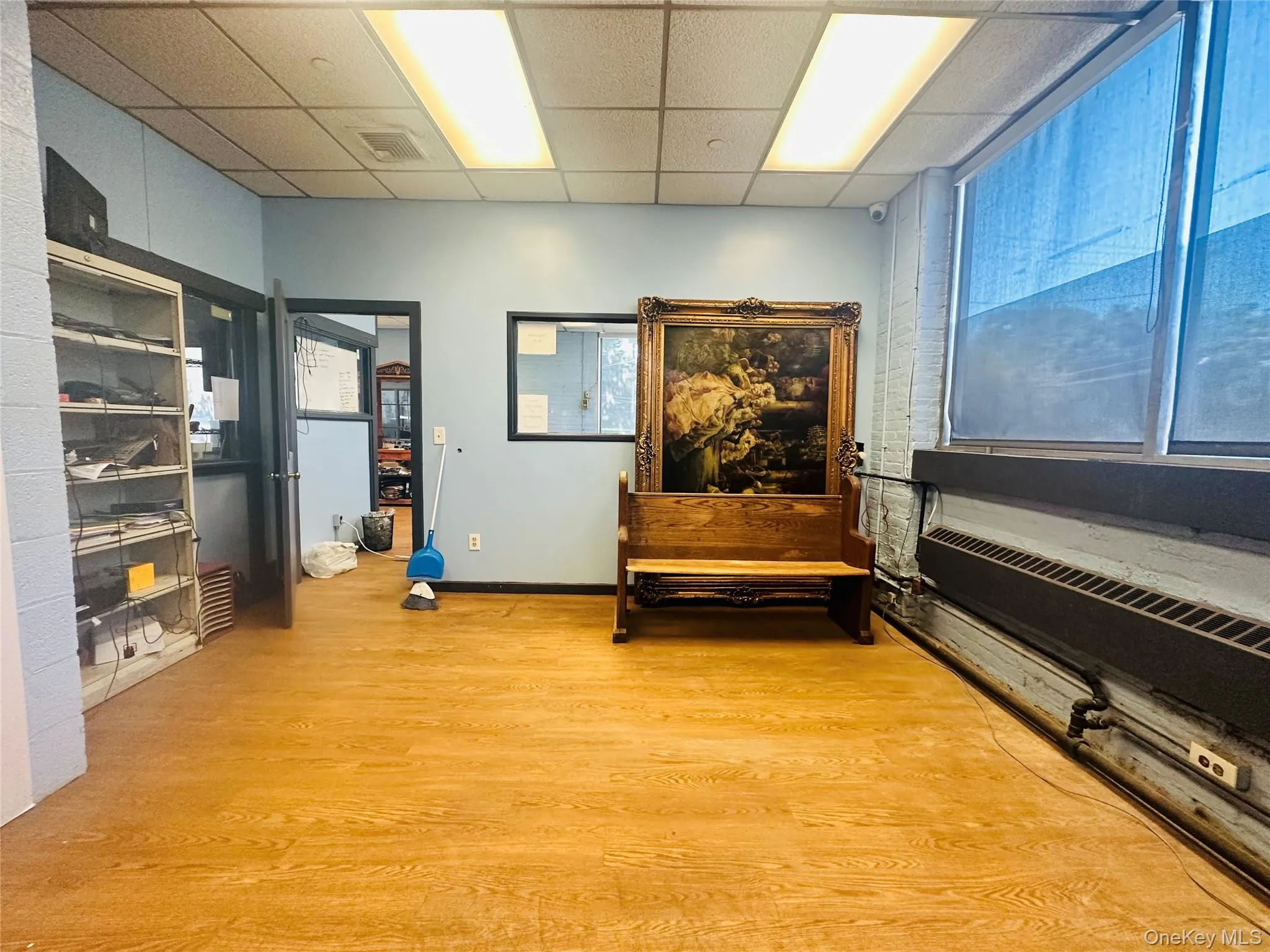 Sitting room with a paneled ceiling, baseboards, visible vents, light wood-style floors, and radiator heating unit Sitting room with a paneled ceiling, baseboards, visible vents, light wood-style floors, and radiator heating unit