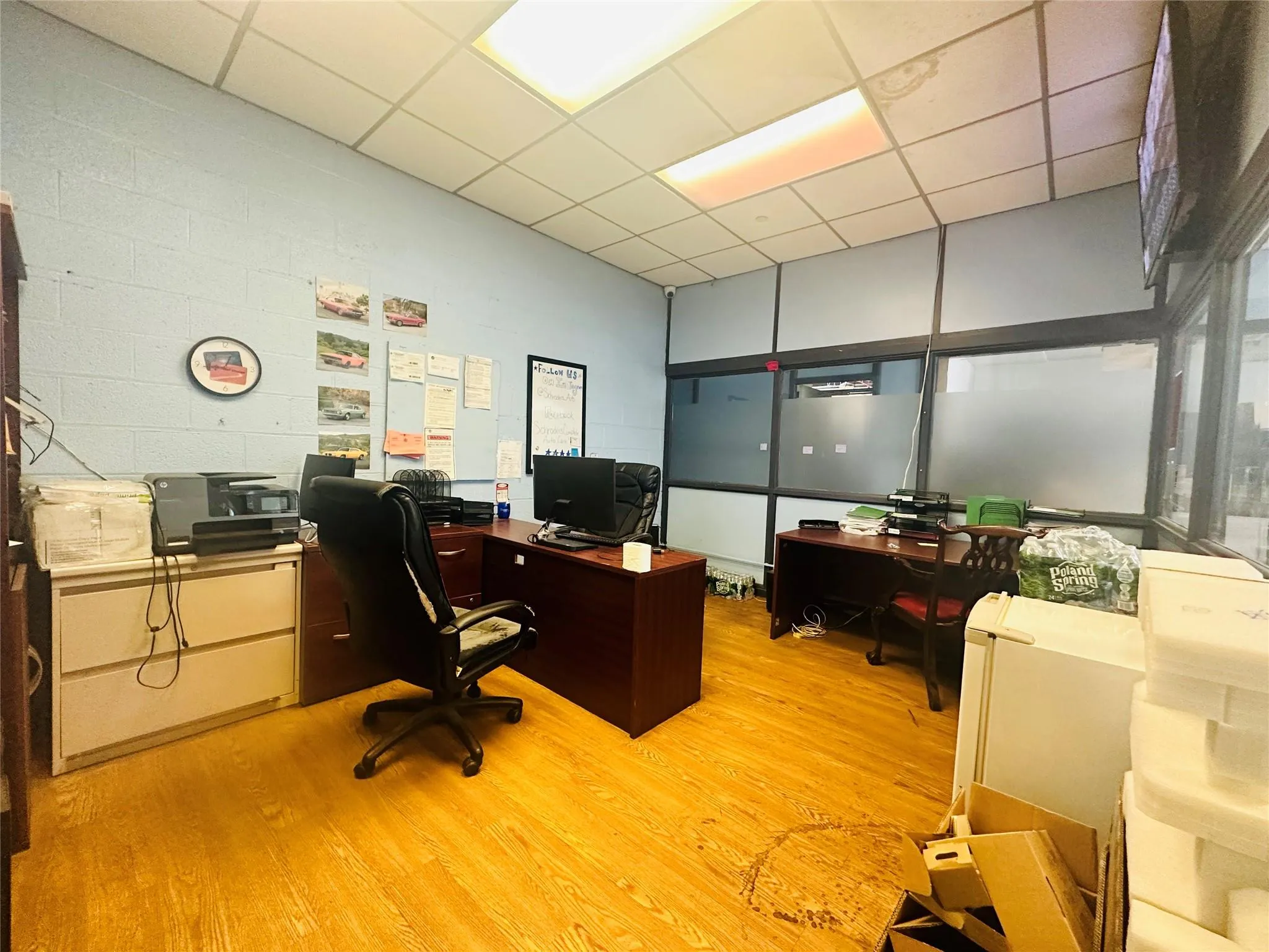 Home office featuring light wood-type flooring, concrete block wall, and a drop ceiling Home office featuring light wood-type flooring, concrete block wall, and a drop ceiling