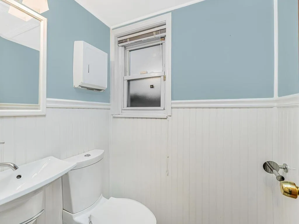 Half bathroom featuring a wainscoted wall, a sink, and toilet Half bathroom featuring a wainscoted wall, a sink, and toilet