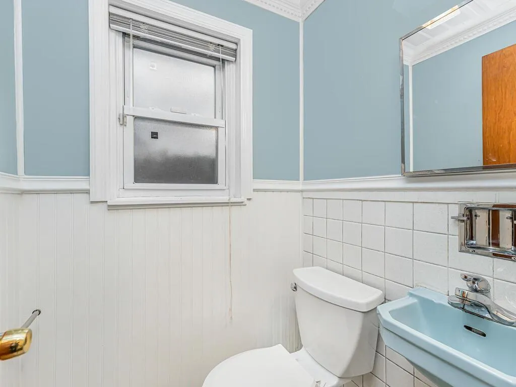 Bathroom with wainscoting, toilet, and a sink Bathroom with wainscoting, toilet, and a sink