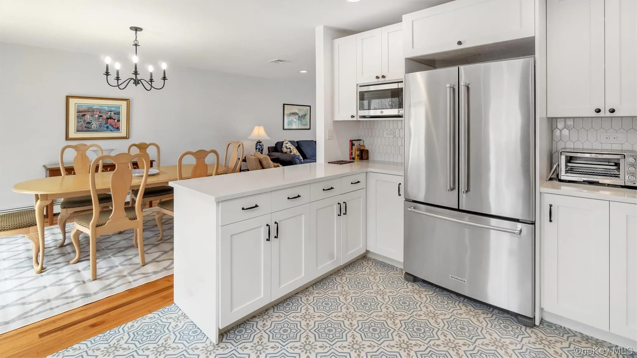 Kitchen featuring a chandelier, stainless steel appliances, light countertops, backsplash, and a peninsula Kitchen featuring a chandelier, stainless steel appliances, light countertops, backsplash, and a peninsula