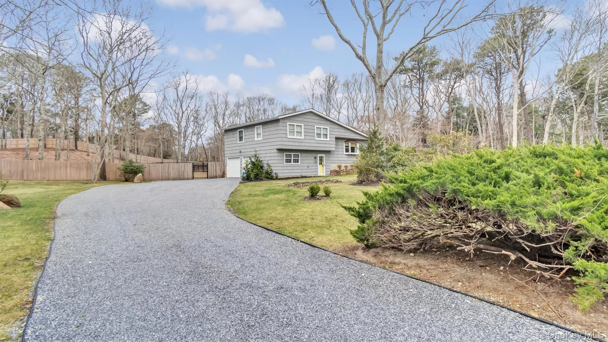 View of home's exterior featuring a lawn, gravel driveway, fence, and a garage View of home's exterior featuring a lawn, gravel driveway, fence, and a garage
