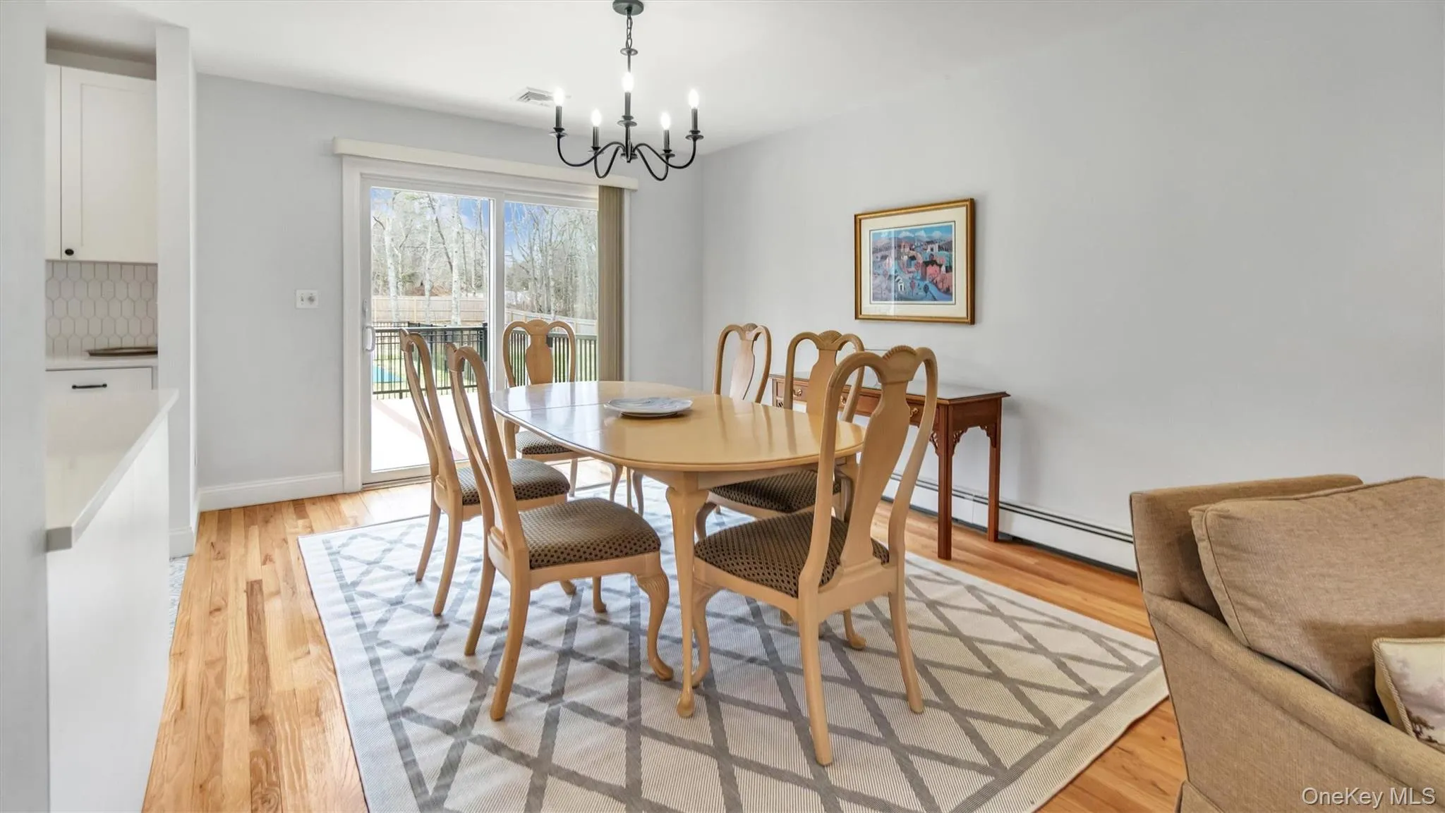 Dining area with a baseboard radiator, a chandelier, light wood-style flooring, baseboards, and visible vents Dining area with a baseboard radiator, a chandelier, light wood-style flooring, baseboards, and visible vents