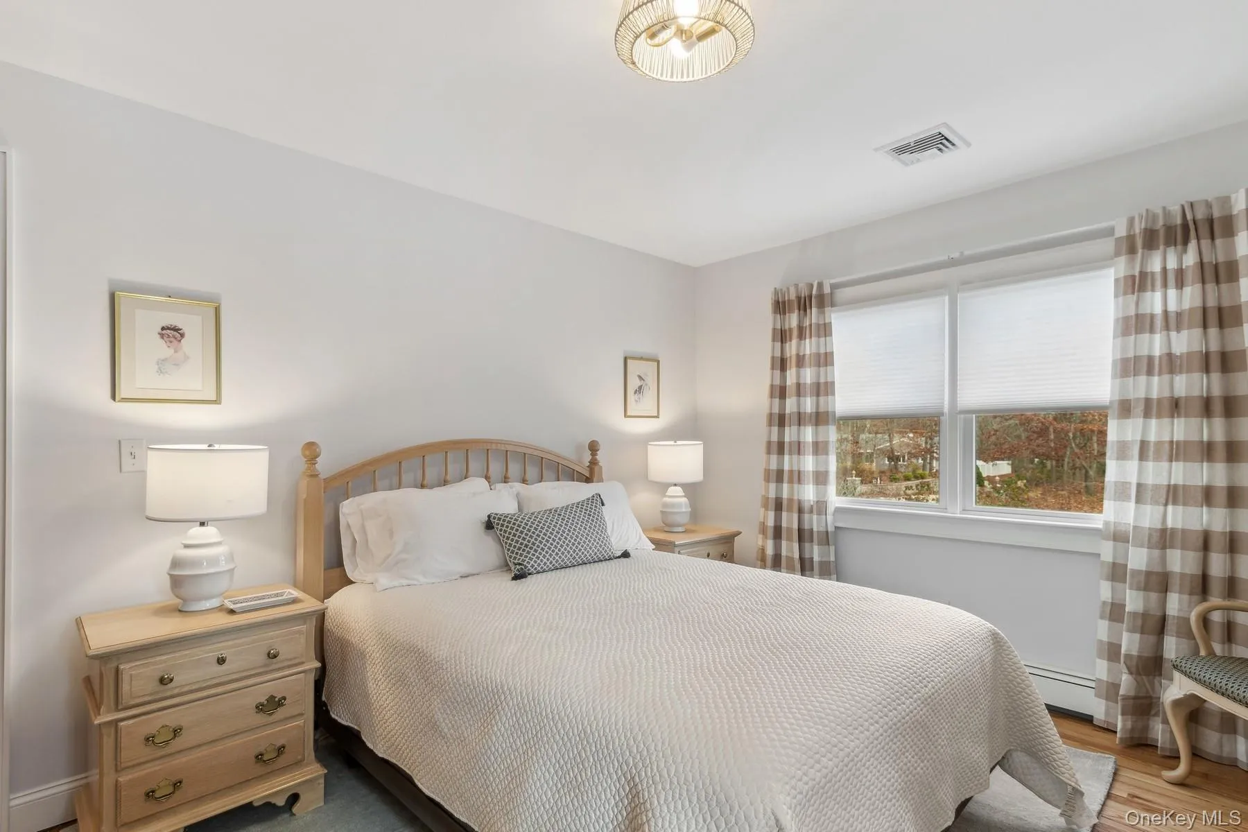 Bedroom featuring a baseboard radiator, wood finished floors, and visible vents Bedroom featuring a baseboard radiator, wood finished floors, and visible vents