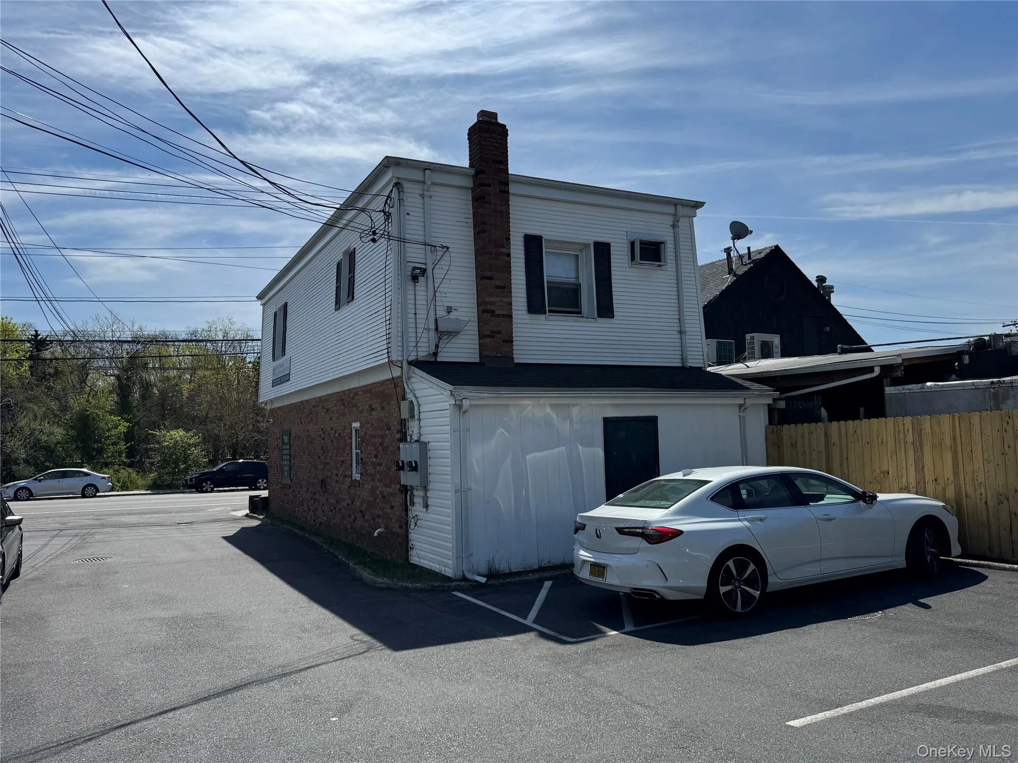 View of side of home with a chimney, fence, and uncovered parking View of side of home with a chimney, fence, and uncovered parking