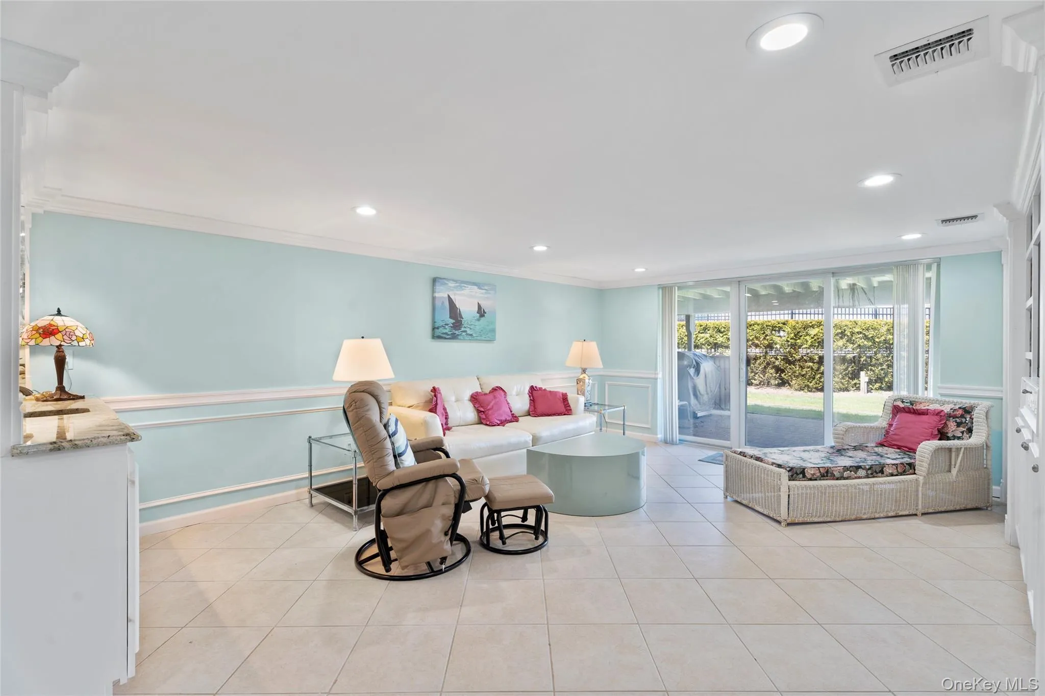 Living area with visible vents, a decorative wall, light tile patterned floors, and crown molding Living area with visible vents, a decorative wall, light tile patterned floors, and crown molding