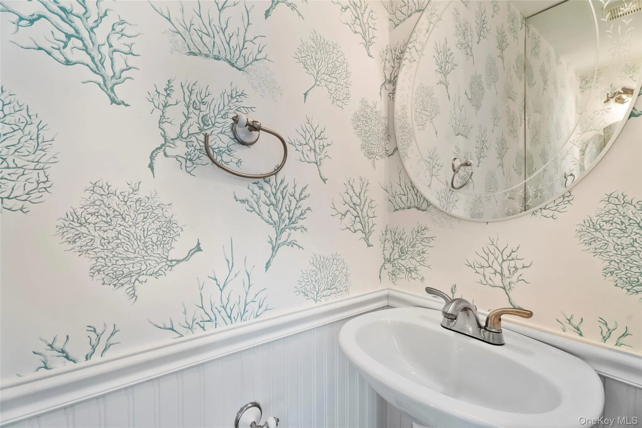 Bathroom featuring a wainscoted wall, a sink, and wallpapered walls Bathroom featuring a wainscoted wall, a sink, and wallpapered walls