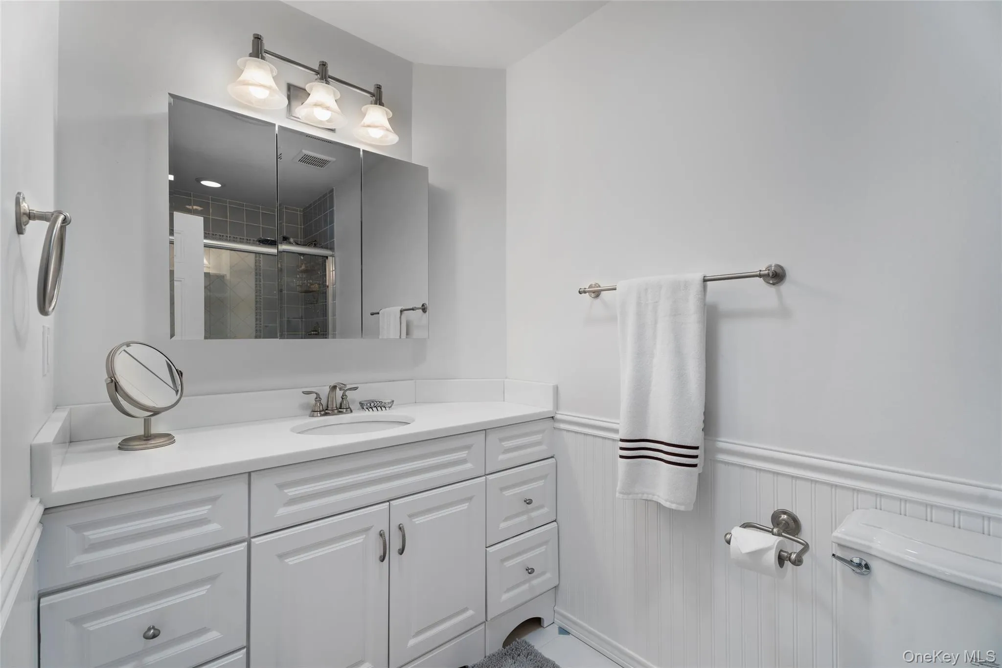 Full bath with vanity, toilet, a stall shower, and wainscoting Full bath with vanity, toilet, a stall shower, and wainscoting