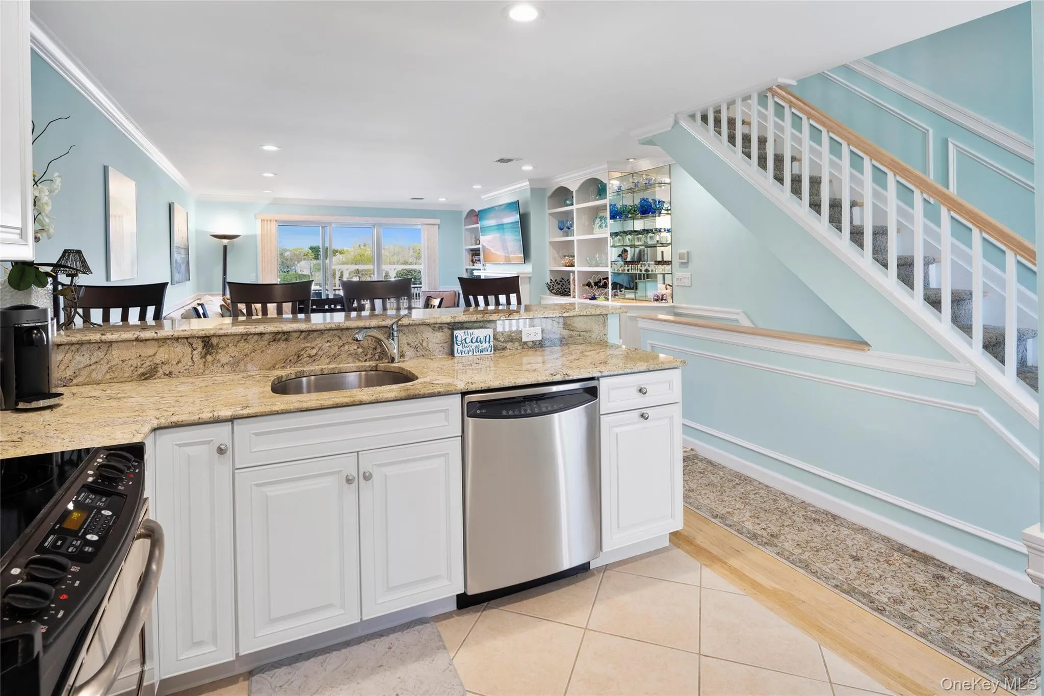 Kitchen featuring light stone counters, light tile patterned floors, a sink, crown molding, and appliances with stainless steel finishes Kitchen featuring light stone counters, light tile patterned floors, a sink, crown molding, and appliances with stainless steel finishes