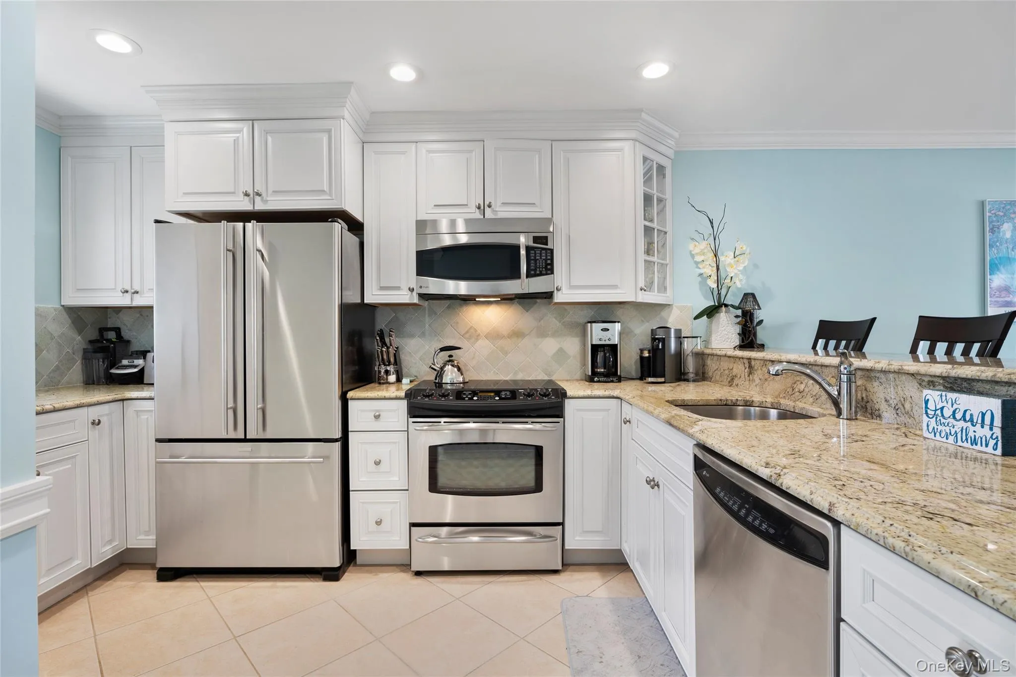 Kitchen featuring white cabinets, a sink, appliances with stainless steel finishes, and tasteful backsplash Kitchen featuring white cabinets, a sink, appliances with stainless steel finishes, and tasteful backsplash