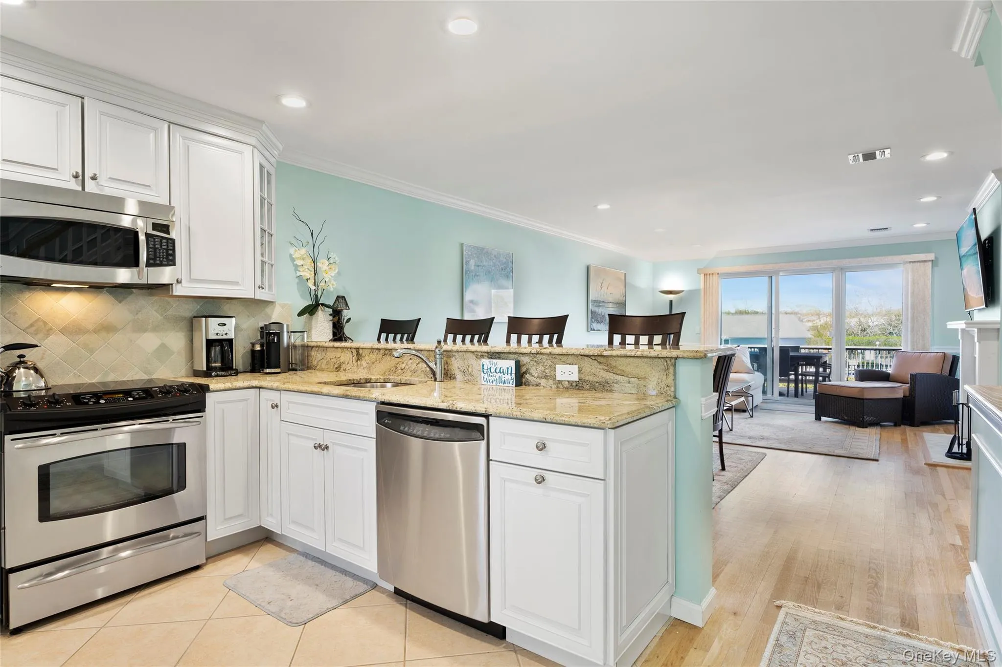 Kitchen featuring white cabinets, stainless steel appliances, a peninsula, a sink, and a breakfast bar area Kitchen featuring white cabinets, stainless steel appliances, a peninsula, a sink, and a breakfast bar area
