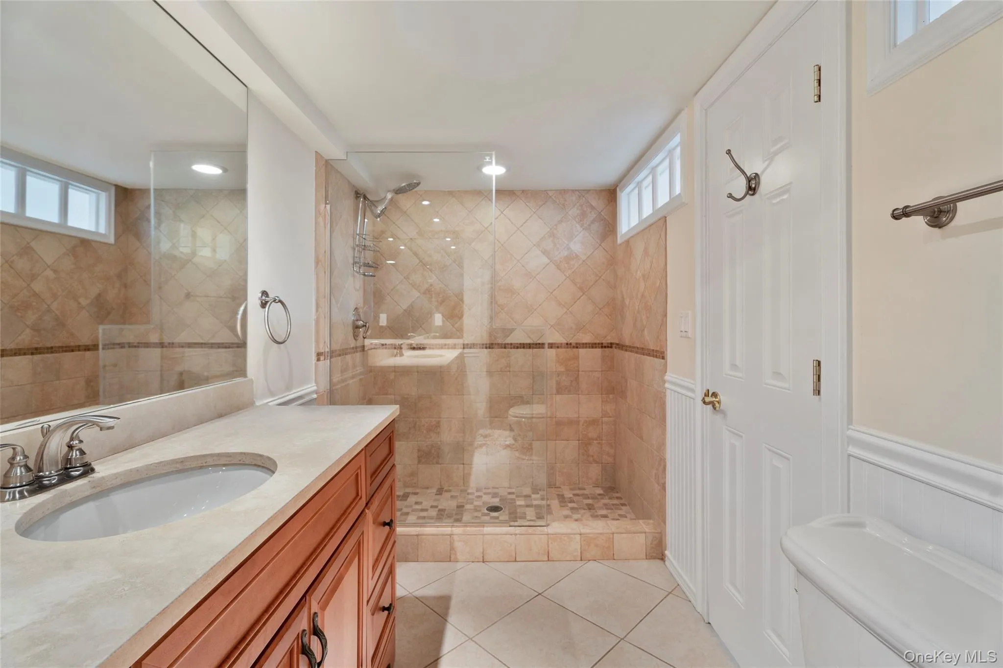 Bathroom featuring vanity, tile patterned flooring, recessed lighting, and a tile shower Bathroom featuring vanity, tile patterned flooring, recessed lighting, and a tile shower
