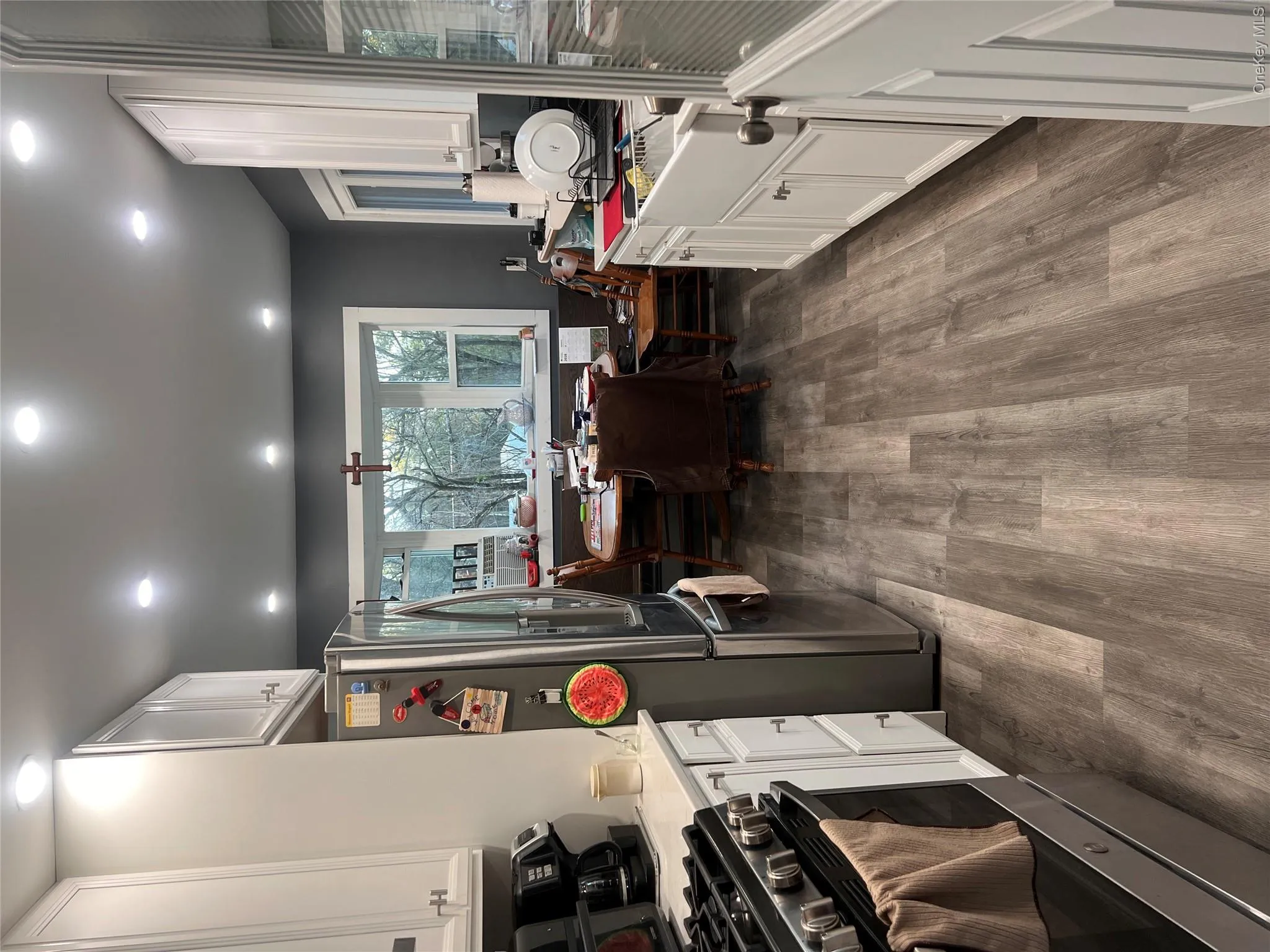 Kitchen featuring white cabinetry, fridge, dark wood-type flooring, stainless steel range, and recessed lighting Kitchen featuring white cabinetry, fridge, dark wood-type flooring, stainless steel range, and recessed lighting