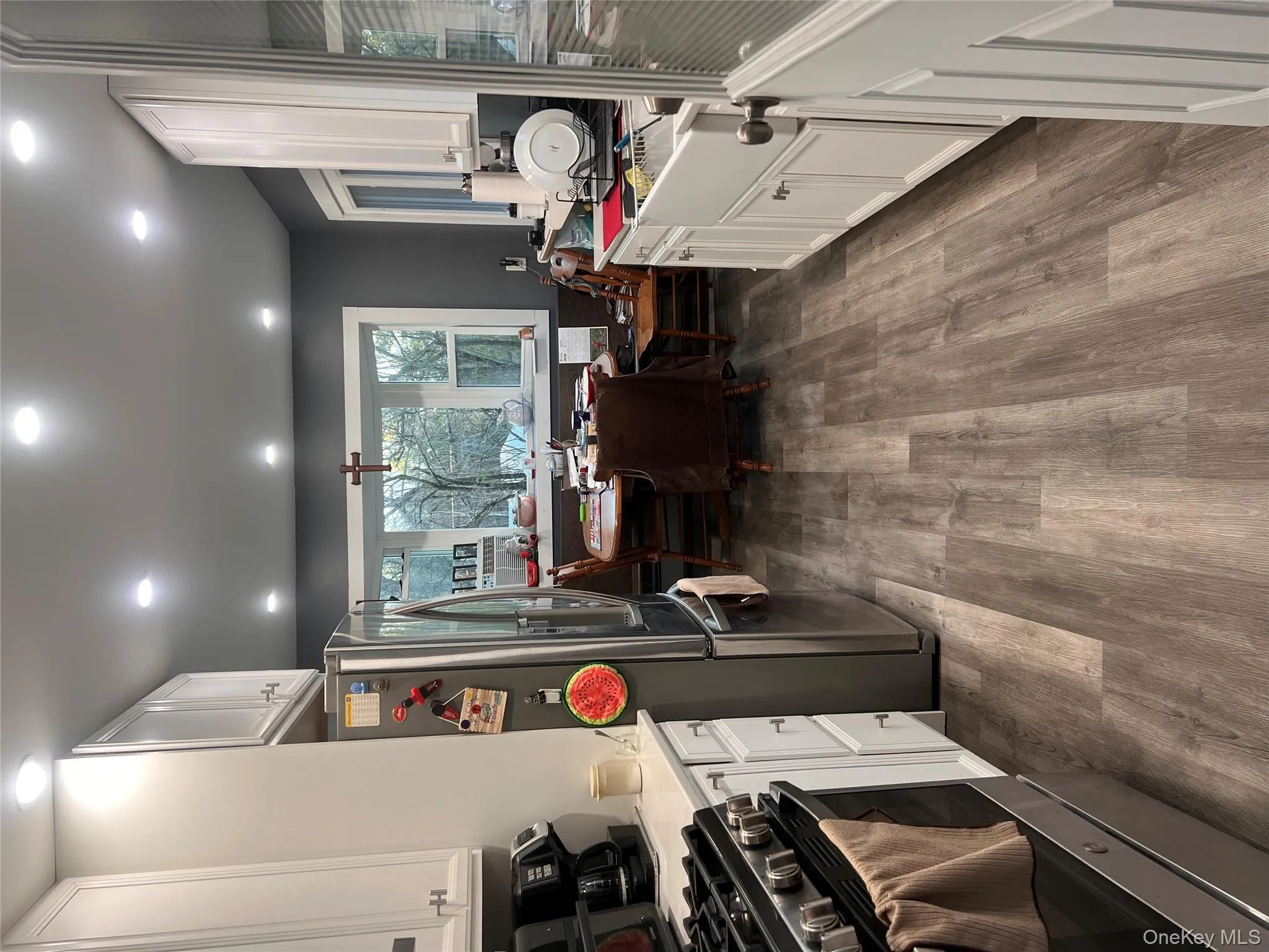 Kitchen featuring white cabinetry, fridge, dark wood-type flooring, stainless steel range, and recessed lighting Kitchen featuring white cabinetry, fridge, dark wood-type flooring, stainless steel range, and recessed lighting